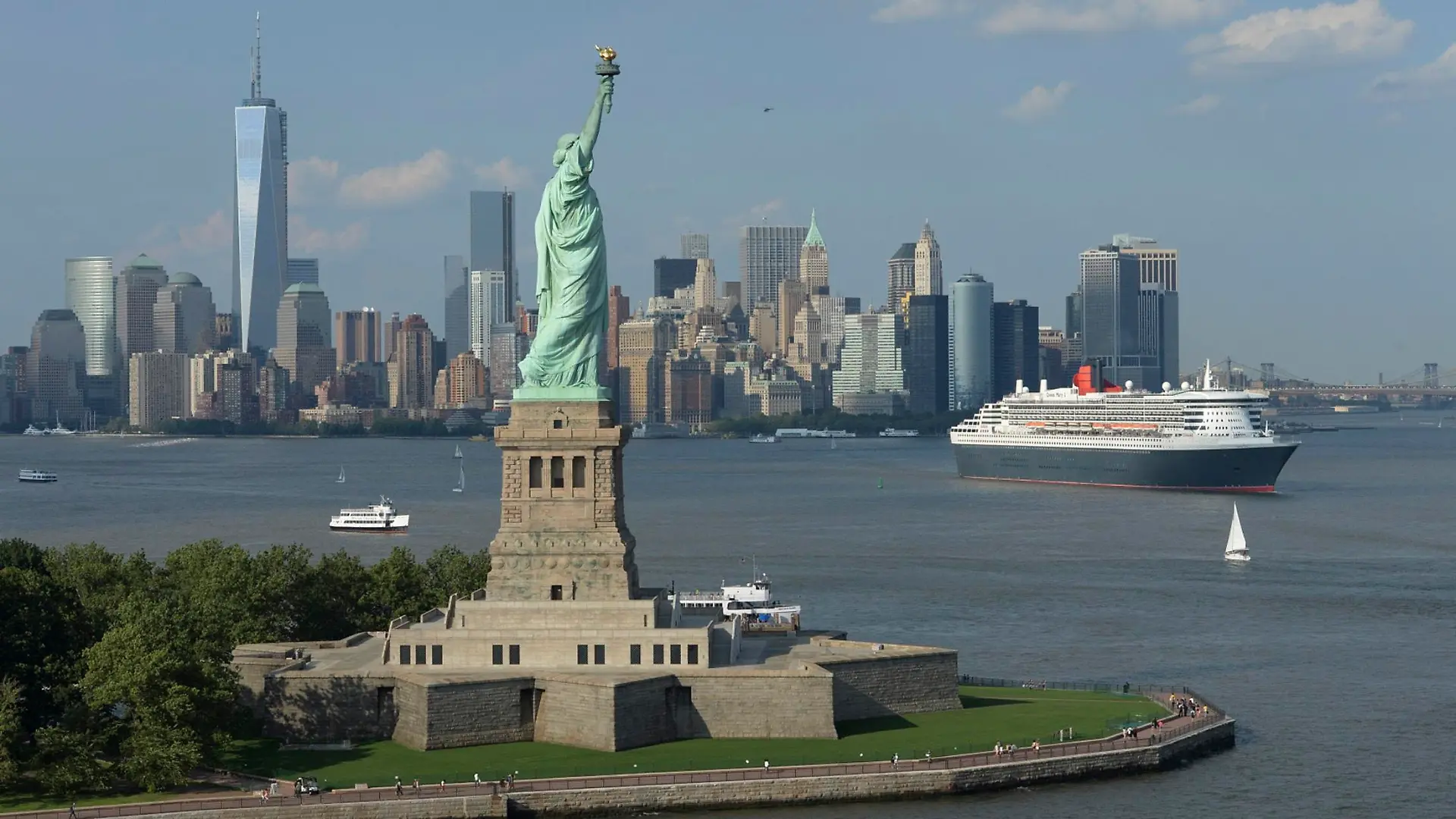 Cunard Line's flagship Queen Mary 2 is seen near the Statue of Liberty (front) and Manhattan skyline in this aerial image, as it leaves for Southampton, Britain, from the New York harbor on July 6, 2013. The ocean liner celebrated its milestone 200th transatlantic crossing since entering service in 2004. REUTERS/James Morgan/Cunard/Handout (UNTED STATES - Tags: SOCIETY TRANSPORT TRAVEL) ATTENTION EDITORS - THIS IMAGE WAS PROVIDED BY A THIRD PARTY. FOR EDITORIAL USE ONLY. NOT FOR SALE FOR MARKETING OR ADVERTISING CAMPAIGNS. NO SALES. NO ARCHIVES. THIS PICTURE IS DISTRIBUTED EXACTLY AS RECEIVED BY REUTERS, AS A SERVICE TO CLIENTS. MANDATORY CREDIT