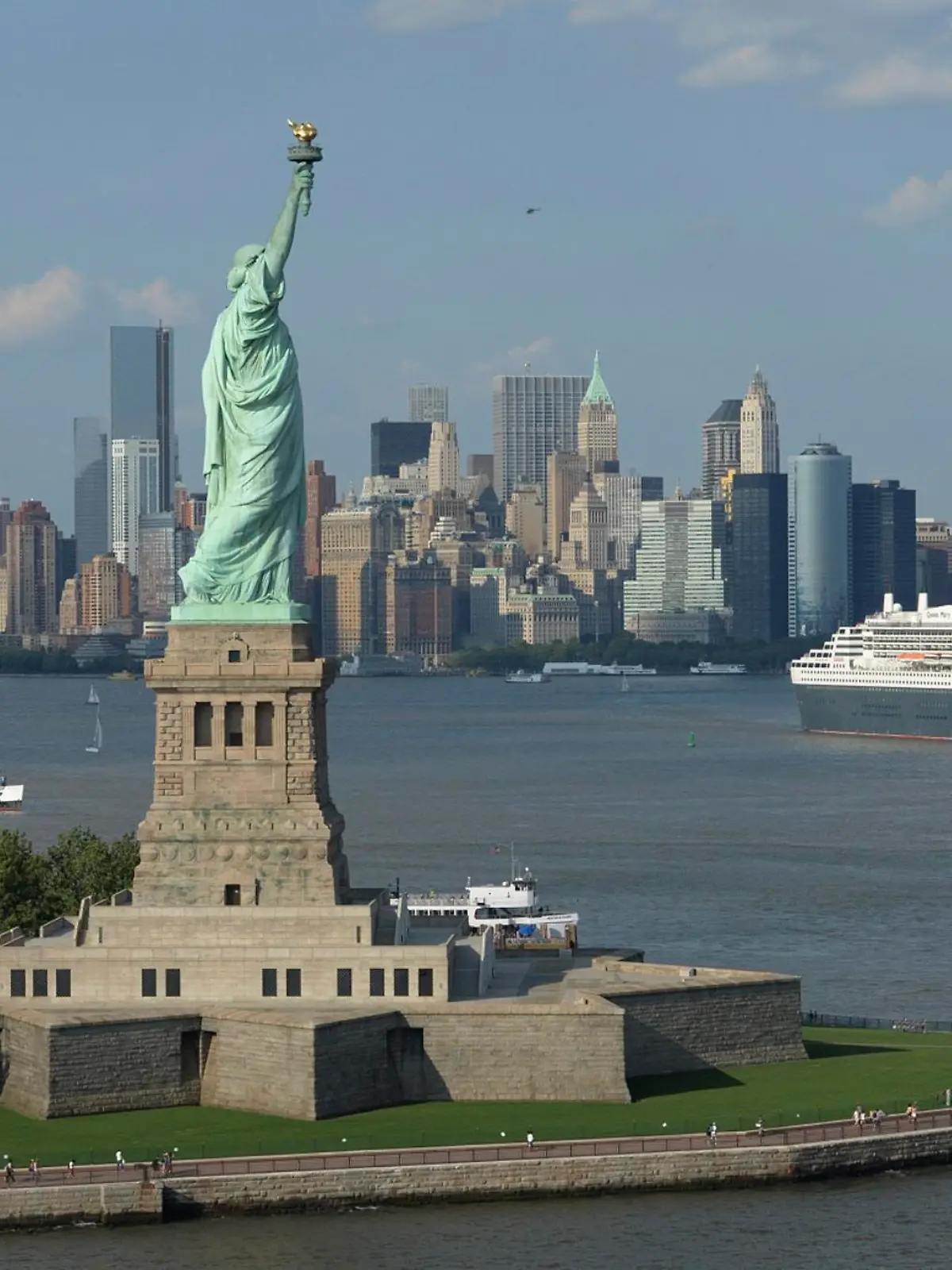 Cunard Line's flagship Queen Mary 2 is seen near the Statue of Liberty (front) and Manhattan skyline in this aerial image, as it leaves for Southampton, Britain, from the New York harbor on July 6, 2013. The ocean liner celebrated its milestone 200th transatlantic crossing since entering service in 2004. REUTERS/James Morgan/Cunard/Handout (UNTED STATES - Tags: SOCIETY TRANSPORT TRAVEL) ATTENTION EDITORS - THIS IMAGE WAS PROVIDED BY A THIRD PARTY. FOR EDITORIAL USE ONLY. NOT FOR SALE FOR MARKETING OR ADVERTISING CAMPAIGNS. NO SALES. NO ARCHIVES. THIS PICTURE IS DISTRIBUTED EXACTLY AS RECEIVED BY REUTERS, AS A SERVICE TO CLIENTS. MANDATORY CREDIT