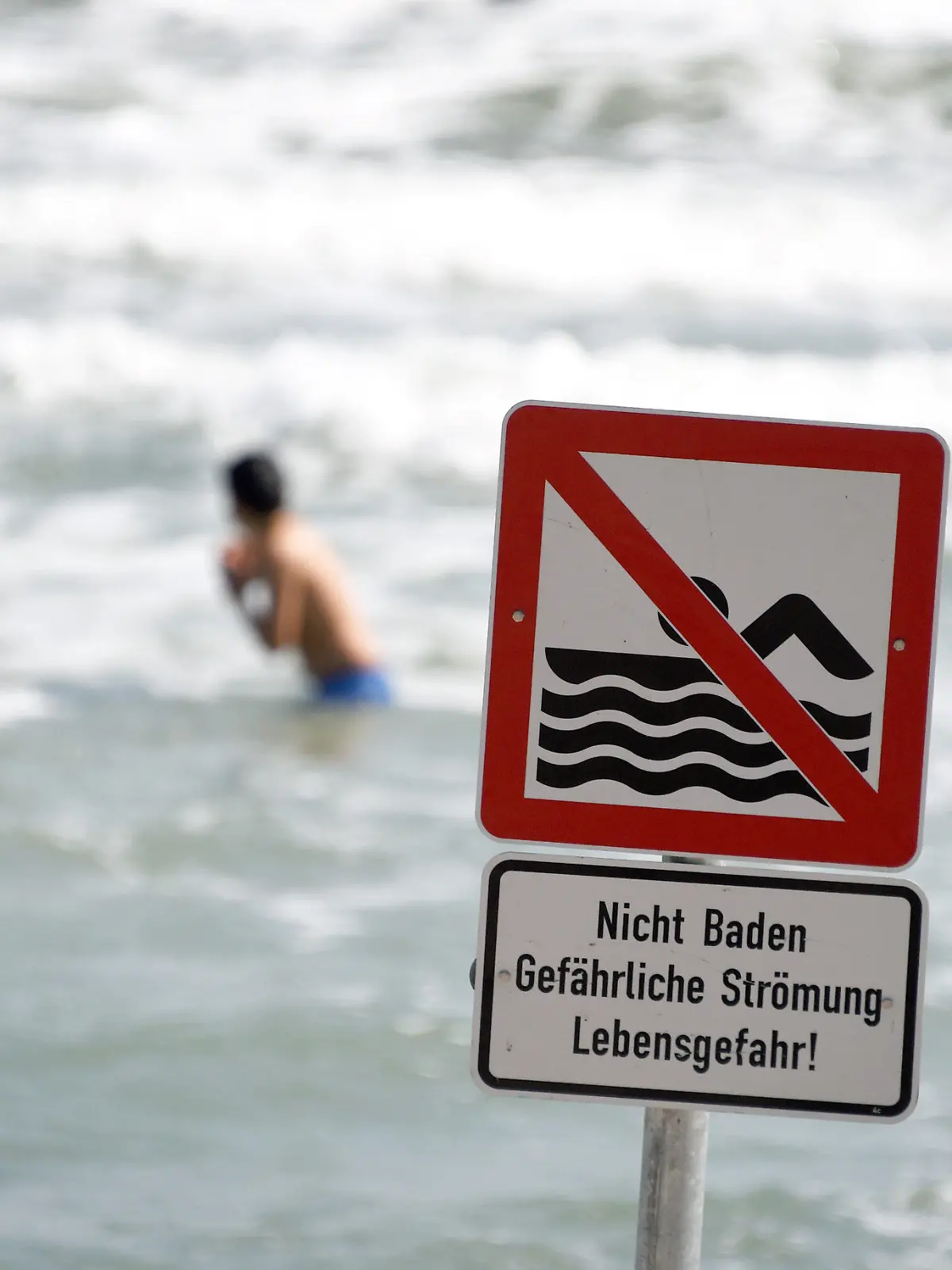 Ein Schild "Nicht Baden Gefährliche Strömung Lebensgefahr!" warnt am 22.07.2014 am Ostseestrand von Timmendorfer Strand (Schleswig-Holstein) die Besucher. Wegen starker Strömung herrscht hier ein Badeverbot. Nach den tödlichen Badeunfällen an der Ostsee hat die Polizei an die Badegäste appelliert, rote Flaggen der DLRG und direkt am Wasser aufgestellte Hinweisschilder zu beachten. Foto: Carsten Rehder/dpa (Zu dpa "Polizei mahnt Badegäste nach Unfällen zur Besonnenheit" vom 22.07.2014) +++(c) dpa - Bildfunk+++