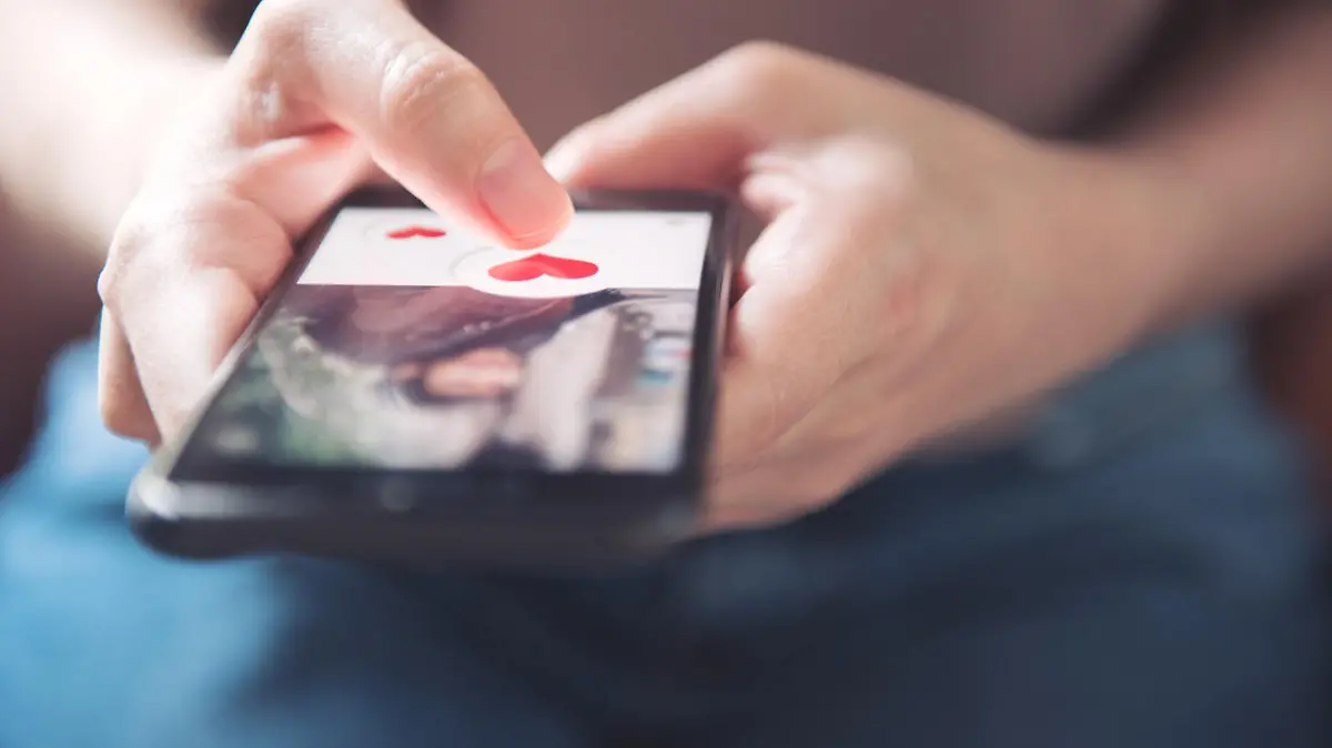 Finger of woman pushing heart icon on screen in mobile smartphone application. Online dating app, valentine's day concept.