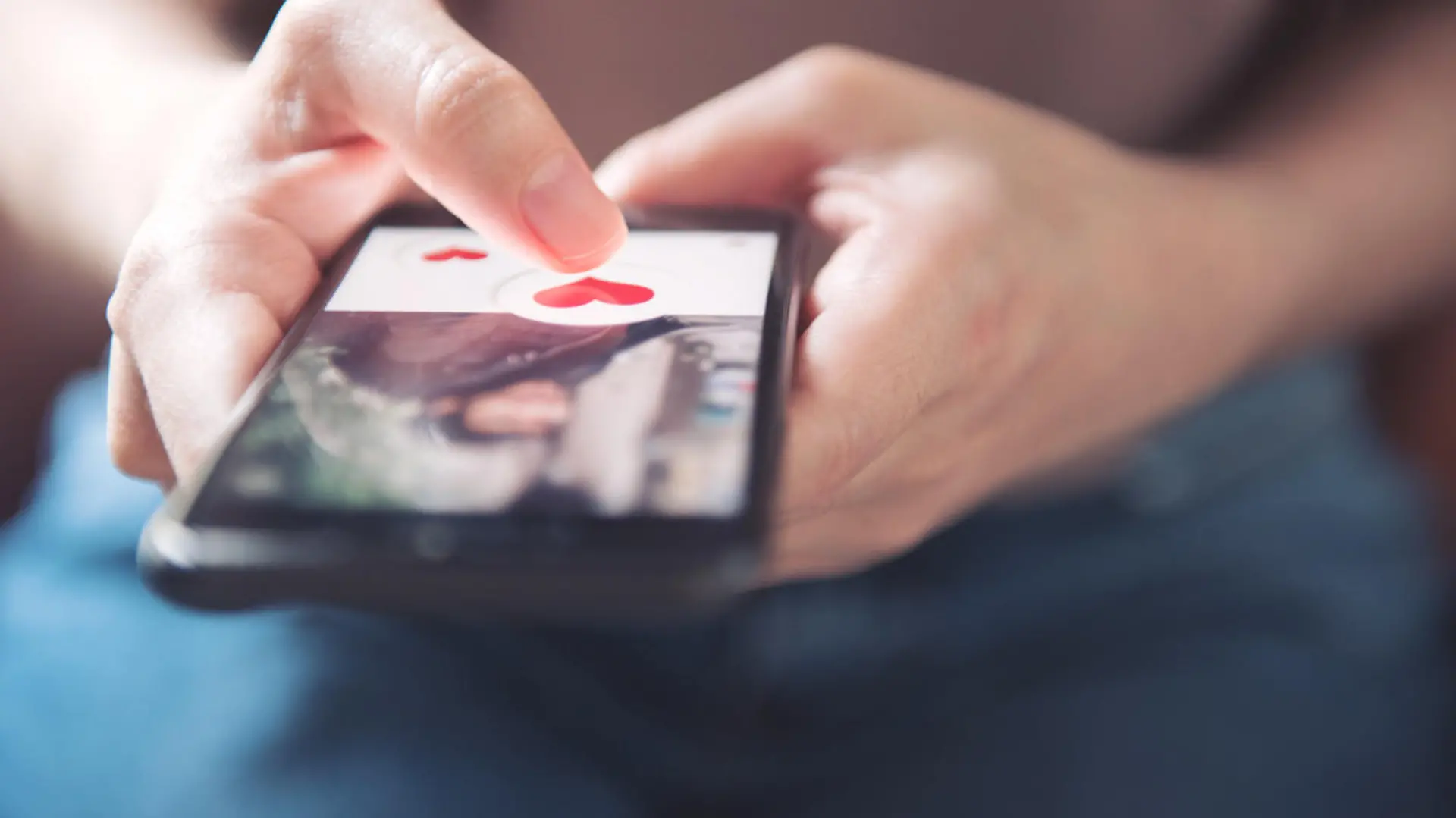 Finger of woman pushing heart icon on screen in mobile smartphone application. Online dating app, valentine's day concept.