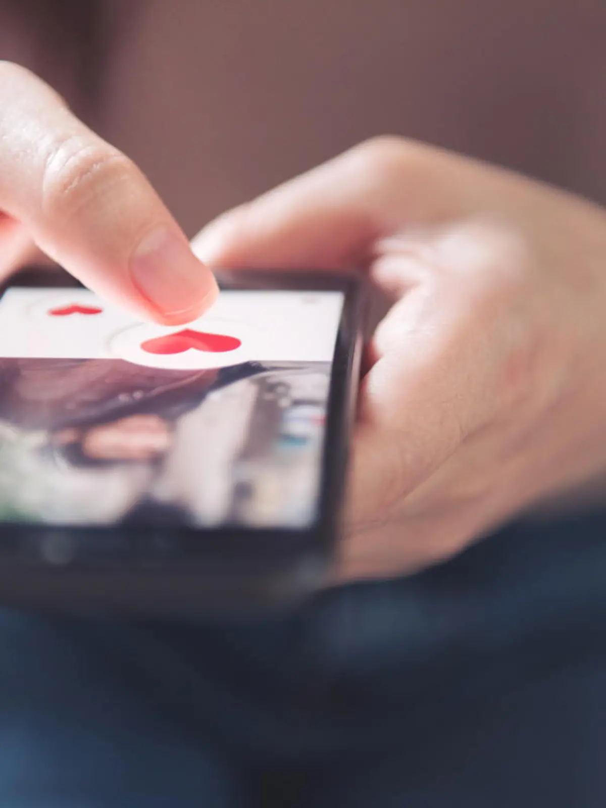 Finger of woman pushing heart icon on screen in mobile smartphone application. Online dating app, valentine's day concept.