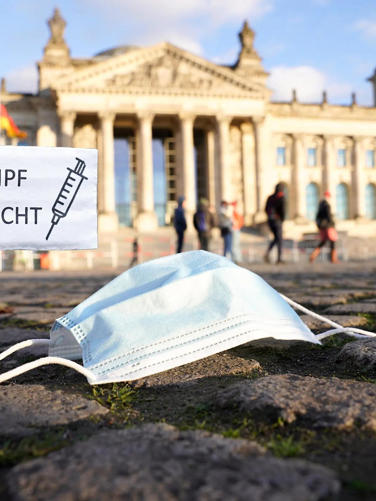Symbolfoto Deutscher Bundestag mit Mund-Nasen-Schutz und Schild mit der Aufschrift Impfpflicht - Debatte zur Einfuehrung der Impfpflicht gegen Corona/ Covid-19 im Deutschen Bundestag (Fotomontage)