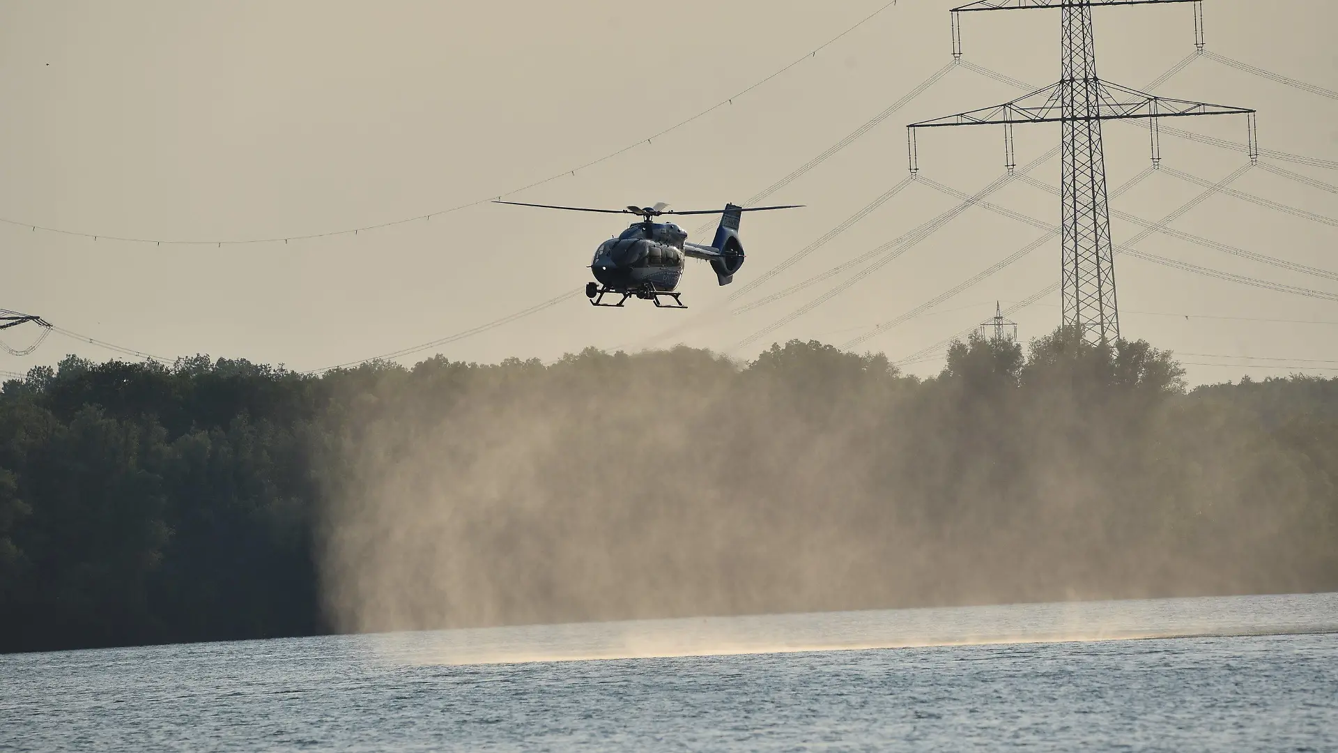 10.06.2023, Nordrhein-Westfalen, Duisburg: Ein Hubschrauber kreist über dem Lohheider See und unterstützt die Suche nach einem Stand-up Paddler. Auf dem Lohheider See in Duisburg ist am Samstagabend ein Mensch ums Leben gekommen. Das Opfer war aus noch unbekannten Gründen beim Stand-up-Paddling ins Wasser gestürzt und danach nicht wieder aufgetaucht, wie die Feuerwehr am Samstag mitteilte. Über mehrere Stunden sei mit Booten, Hubschraubern, Tauchern sowie an Land nach der Person gesucht worden, bis der leblose Körper gegen 21 Uhr geborgen wurde. Ein Notarzt habe nur noch den Tod feststellen können. Angaben zur Identität des Unfallopfers machte die Feuerwehr zunächst nicht. Foto: Alex Forstreuter/dpa +++ dpa-Bildfunk +++