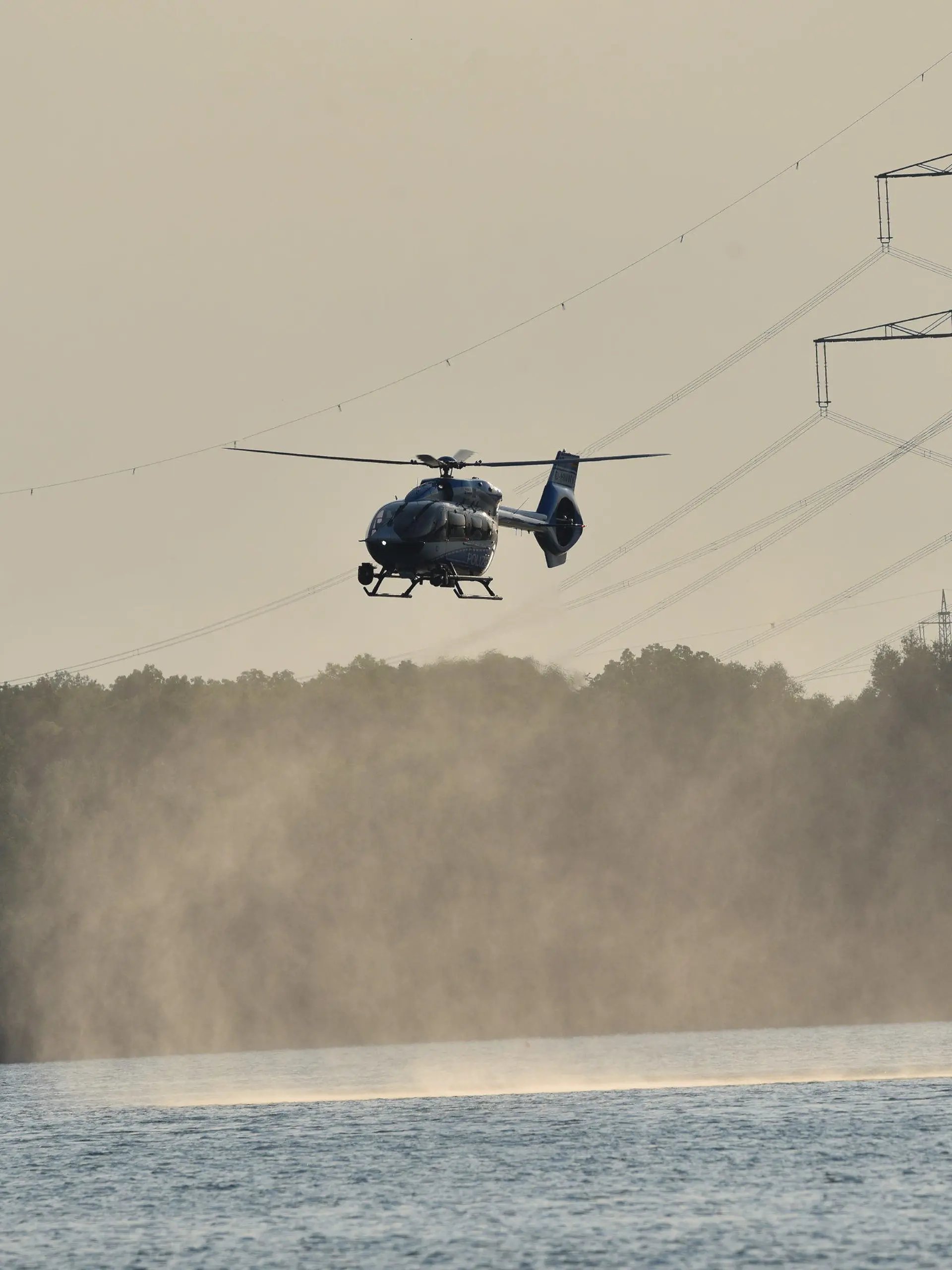 10.06.2023, Nordrhein-Westfalen, Duisburg: Ein Hubschrauber kreist über dem Lohheider See und unterstützt die Suche nach einem Stand-up Paddler. Auf dem Lohheider See in Duisburg ist am Samstagabend ein Mensch ums Leben gekommen. Das Opfer war aus noch unbekannten Gründen beim Stand-up-Paddling ins Wasser gestürzt und danach nicht wieder aufgetaucht, wie die Feuerwehr am Samstag mitteilte. Über mehrere Stunden sei mit Booten, Hubschraubern, Tauchern sowie an Land nach der Person gesucht worden, bis der leblose Körper gegen 21 Uhr geborgen wurde. Ein Notarzt habe nur noch den Tod feststellen können. Angaben zur Identität des Unfallopfers machte die Feuerwehr zunächst nicht. Foto: Alex Forstreuter/dpa +++ dpa-Bildfunk +++