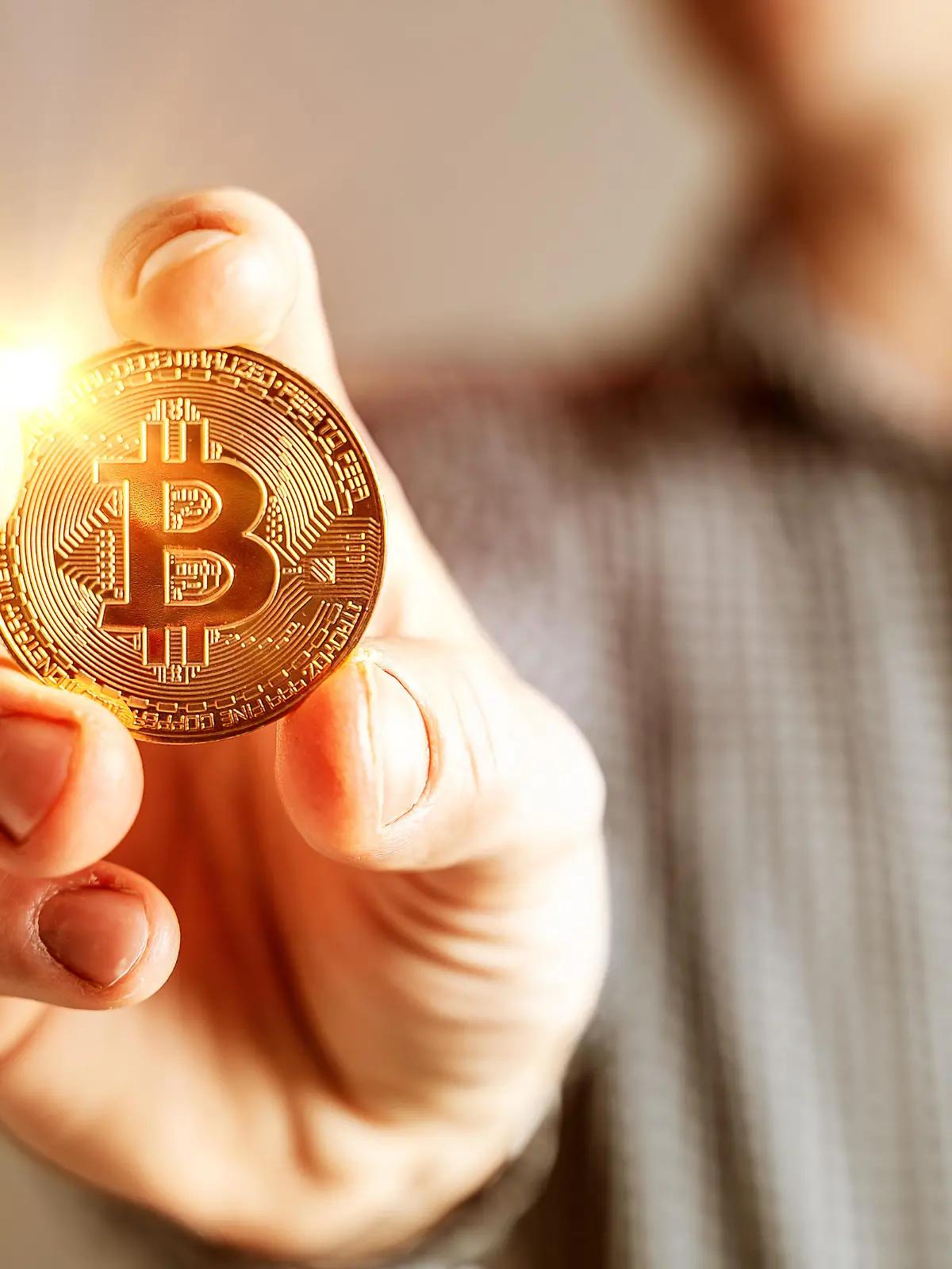 Kryptowährung goldene leuchtende Bitcoin Münze in der Hand eines Mannes Symbol der Kryptowährung elektronisches virtuelles Geld FOTOMONTAGE