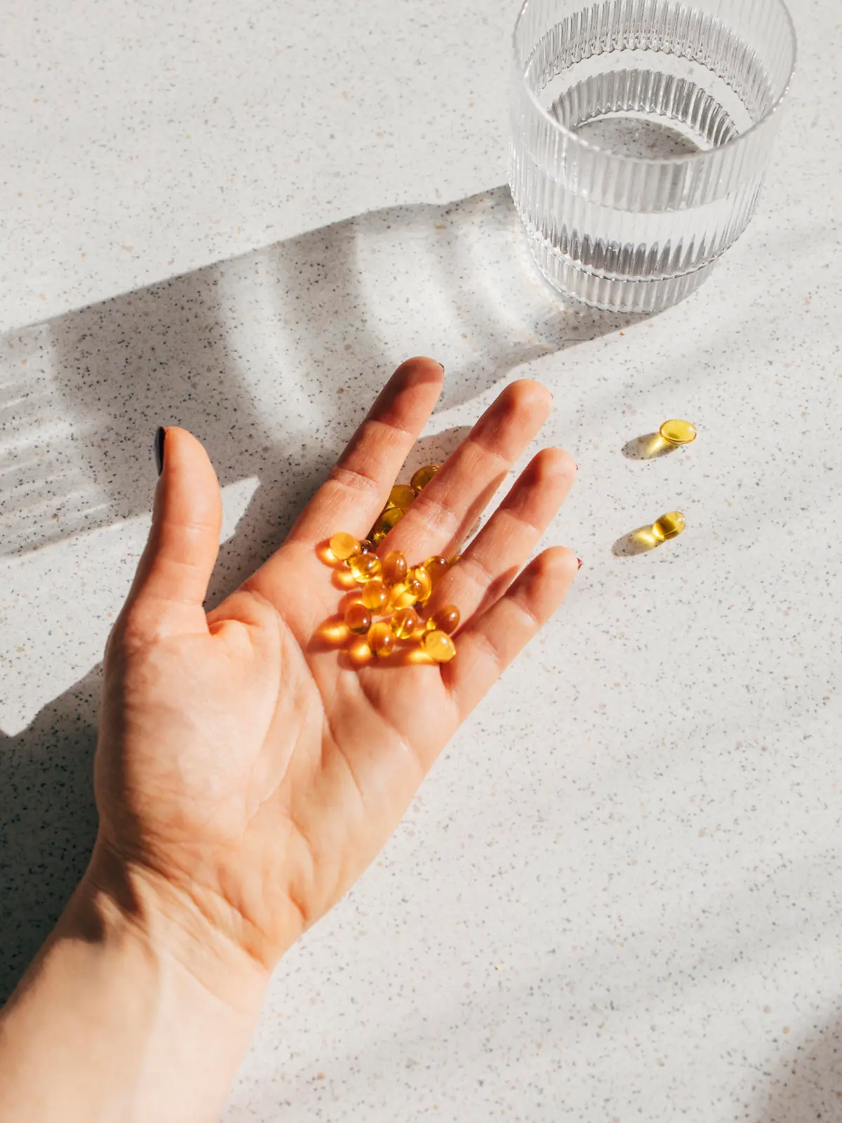 A high angle shot of an unrecognizable person's hand holding a bunch of vitamin D pills.