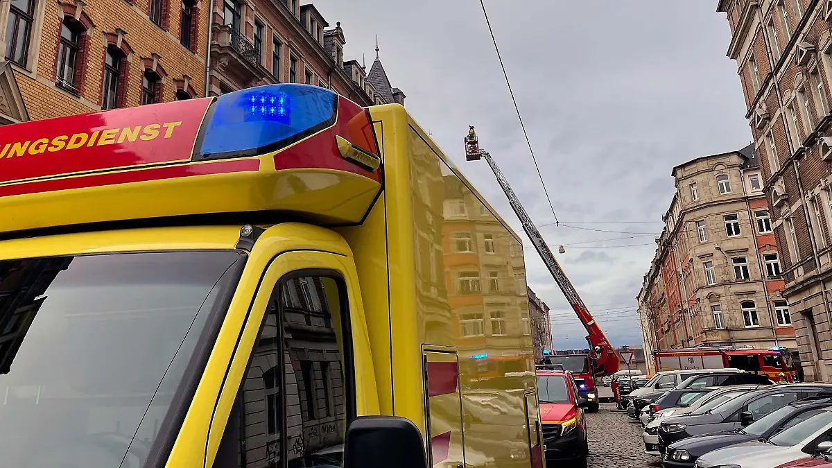 Bild eines Feuerwehreinsatzes in Dresden, bei dem Einsatzkräfte nach einer Person auf einem Dach suchen.