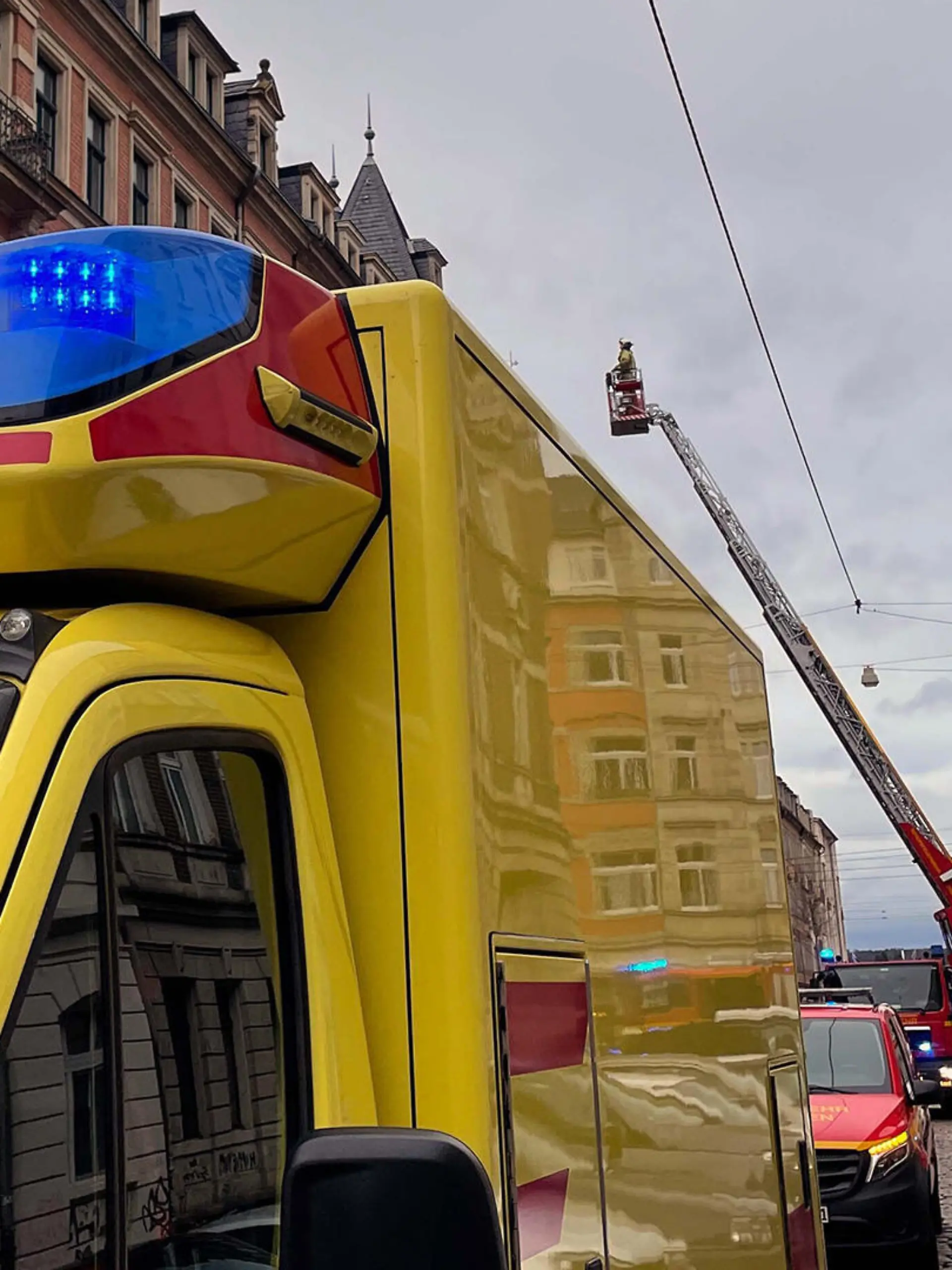 Bild eines Feuerwehreinsatzes in Dresden, bei dem Einsatzkräfte nach einer Person auf einem Dach suchen.
