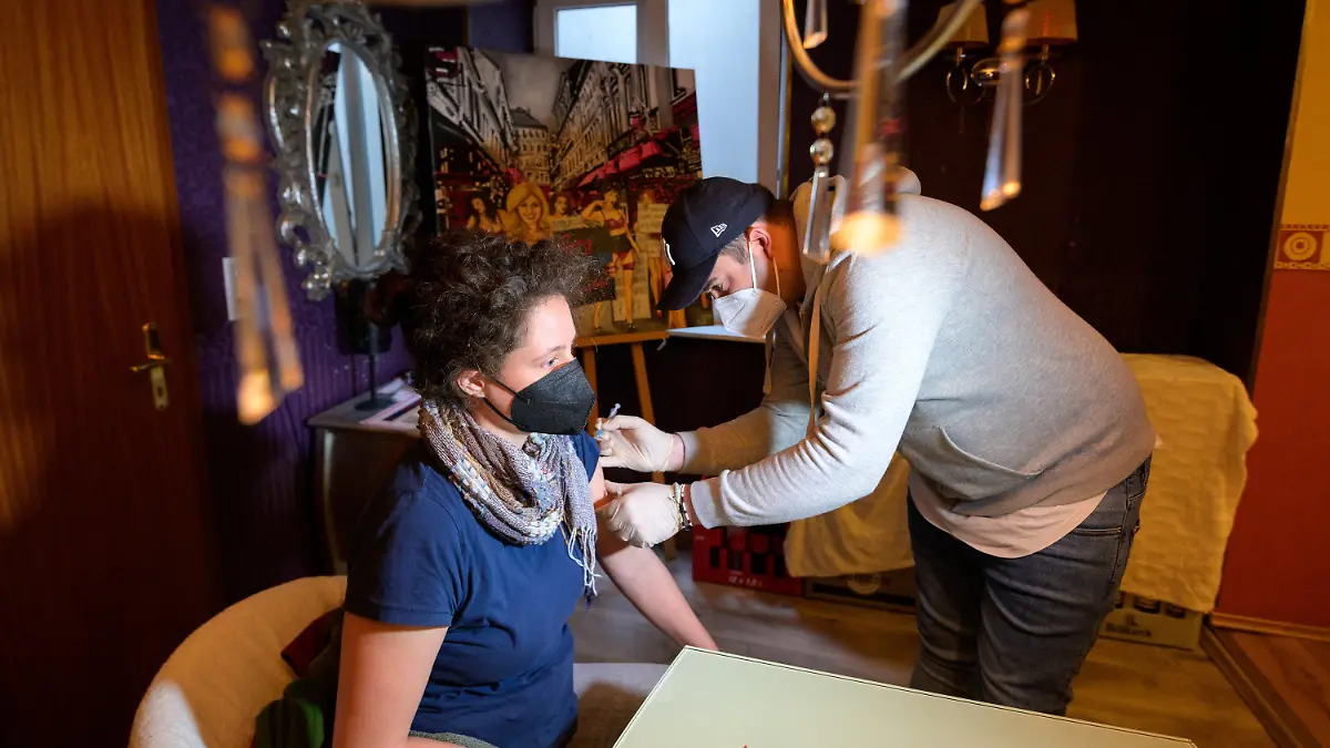06.02.2022, Hamburg: Ricarda lässt sich vor einem Bild der Künstlerin Maaike Dirkx in den Räumen eines Bordells impfen. In einem Bordell in der berühmten Herbertstraße auf der Reeperbahn haben Besucher am Sonntagmorgen ein Impfangebot erhalten. Unter dem Motto «Love Booster» gab es 120 Impfdosen von Biontech und Moderna für angemeldete Impfwillige ab 18 Jahren. Gleichzeitig war noch eine Kunstausstellung zum Thema «Sexy Aufstand Reeperbahn» zu sehen. Foto: Jonas Walzberg/dpa - ACHTUNG: Nur zur redaktionellen Verwendung im Zusammenhang mit der aktuellen Berichterstattung und nur mit vollständiger Nennung des vorstehenden Credits +++ dpa-Bildfunk +++