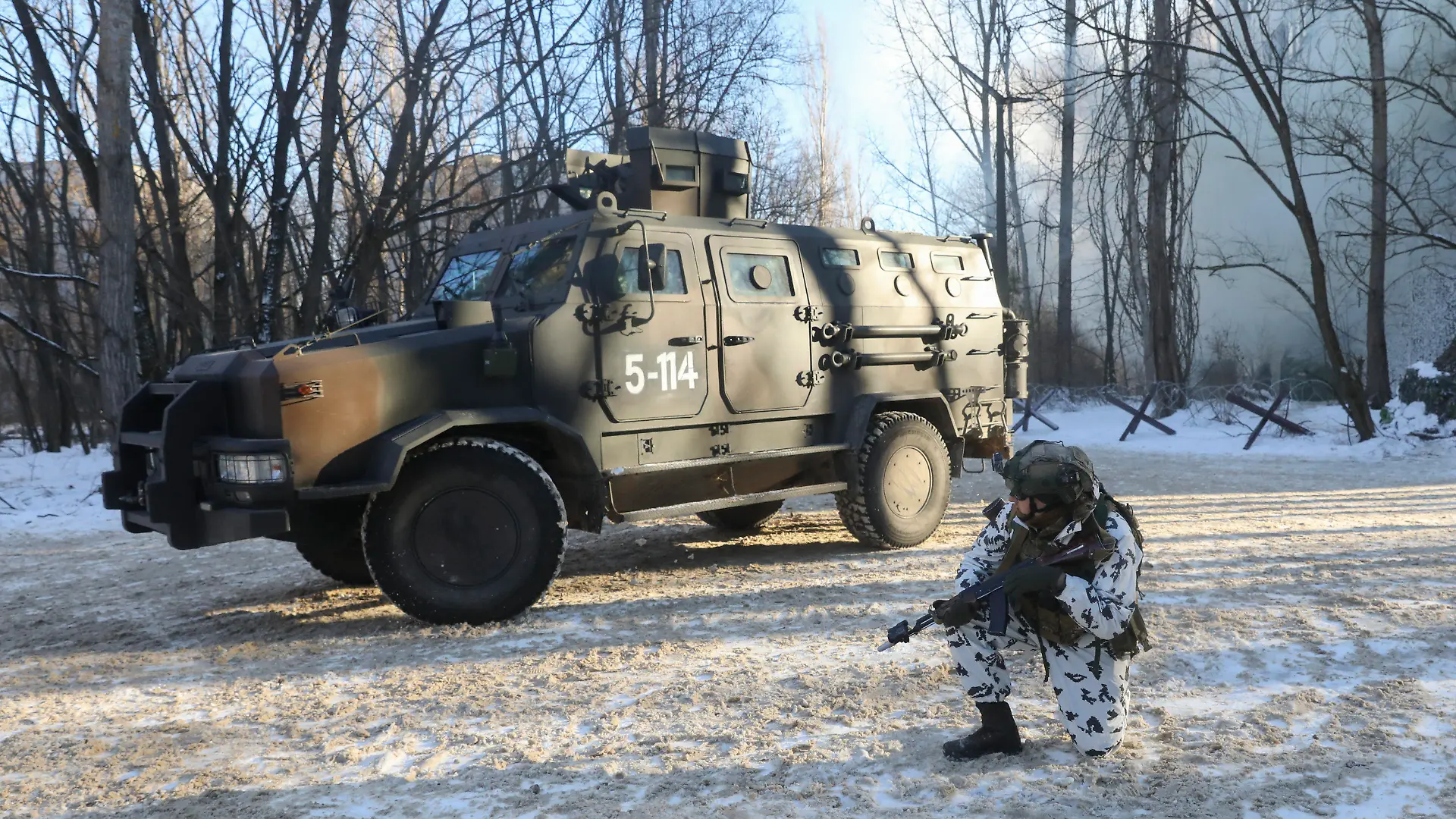 04.02.2022, Ukraine, Prypjat: Ein Soldat der Spezialeinheiten der ukrainischen Nationalgarde kniet während einer Militärübung in der verlassenen Stadt Prypjat in der Nähe des Kernkraftwerks Tschernobyl neben einem Militärfahrzeug. Foto: Mykola Tymchenko/AP/dpa +++ dpa-Bildfunk +++