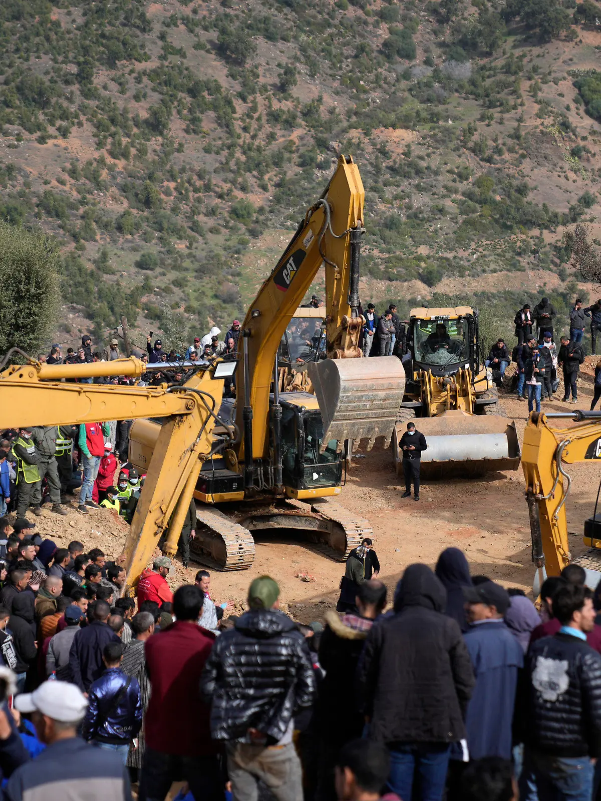 Residents watch civil defense workers and local authorities attempting to rescue a 5 year old boy who fell into a hole near the town of Bab Berred near Chefchaouen, Friday, Feb. 4, 2022 in Ighran. A third day of efforts to rescue a 5-year-old boy who fell into a well in northern Morocco was halted for a time on Friday following concerns about ground stability, fueling despair among those hoping to reach him. The boy, identified as Rayan, fell into a 32-meter (105-feet) deep well located outside his home in the northern village of Ighran in Morocco's Chefchaouen province on Tuesday evening.(AP Photo/Mosa'ab Elshamy)