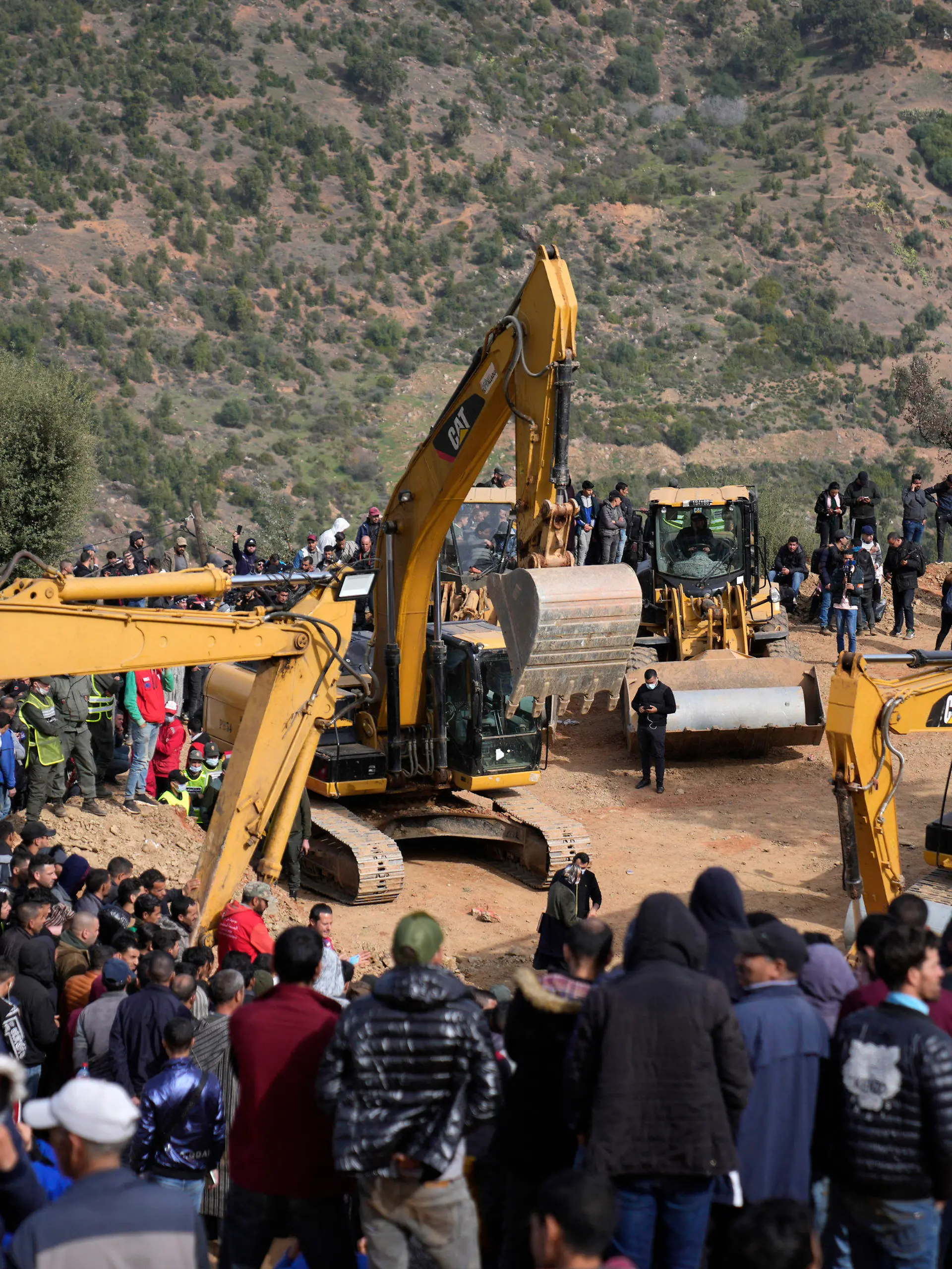 Residents watch civil defense workers and local authorities attempting to rescue a 5 year old boy who fell into a hole near the town of Bab Berred near Chefchaouen, Friday, Feb. 4, 2022 in Ighran. A third day of efforts to rescue a 5-year-old boy who fell into a well in northern Morocco was halted for a time on Friday following concerns about ground stability, fueling despair among those hoping to reach him. The boy, identified as Rayan, fell into a 32-meter (105-feet) deep well located outside his home in the northern village of Ighran in Morocco's Chefchaouen province on Tuesday evening.(AP Photo/Mosa'ab Elshamy)