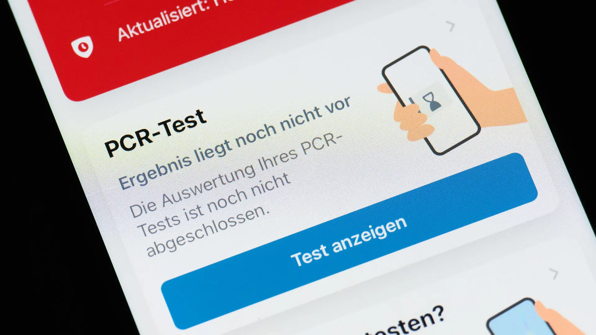 26.01.2022, Niedersachsen, Hannover: ILLUSTRATION - Auf dem Display eines Smartphones mit der Corona-Warn-App steht: ·PCR-Test - Ergebnis liegt noch nicht vor. Die Auswertung Ihres PCR-Tests ist noch nicht abgeschlossen·. Erstmals in der Corona-Pandemie sind binnen eines Tages mehr als 150 000 Neuinfektionen an das Robert Koch-Institut übermittelt worden. Wegen der sprunghaft steigenden Infektionszahlen reichen die derzeitigen Kapazitäten für die besonders genauen PCR-Tests nicht mehr aus. Foto: Julian Stratenschulte/dpa +++ dpa-Bildfunk +++