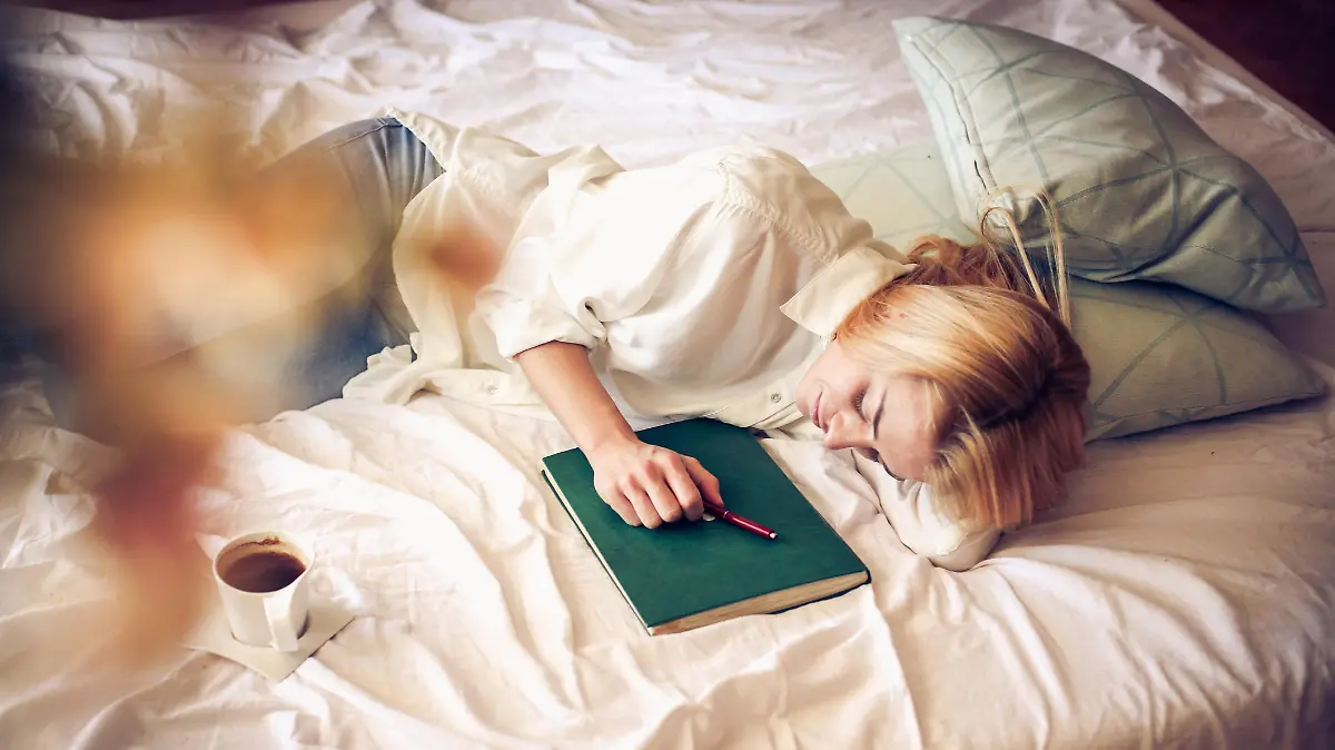 Young student woman sleeping in bed with book.