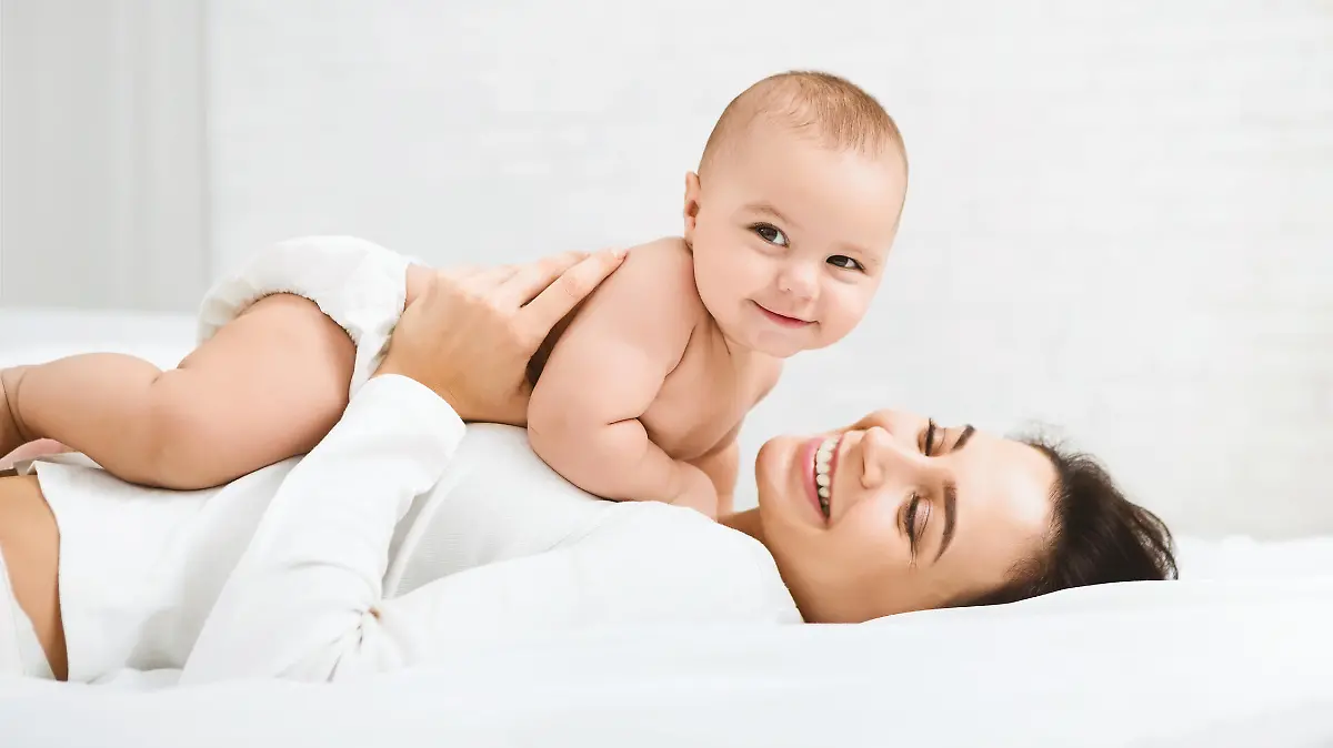 Family having fun together. Mom and baby boy in diaper playing in bedroom, panorama, copy space