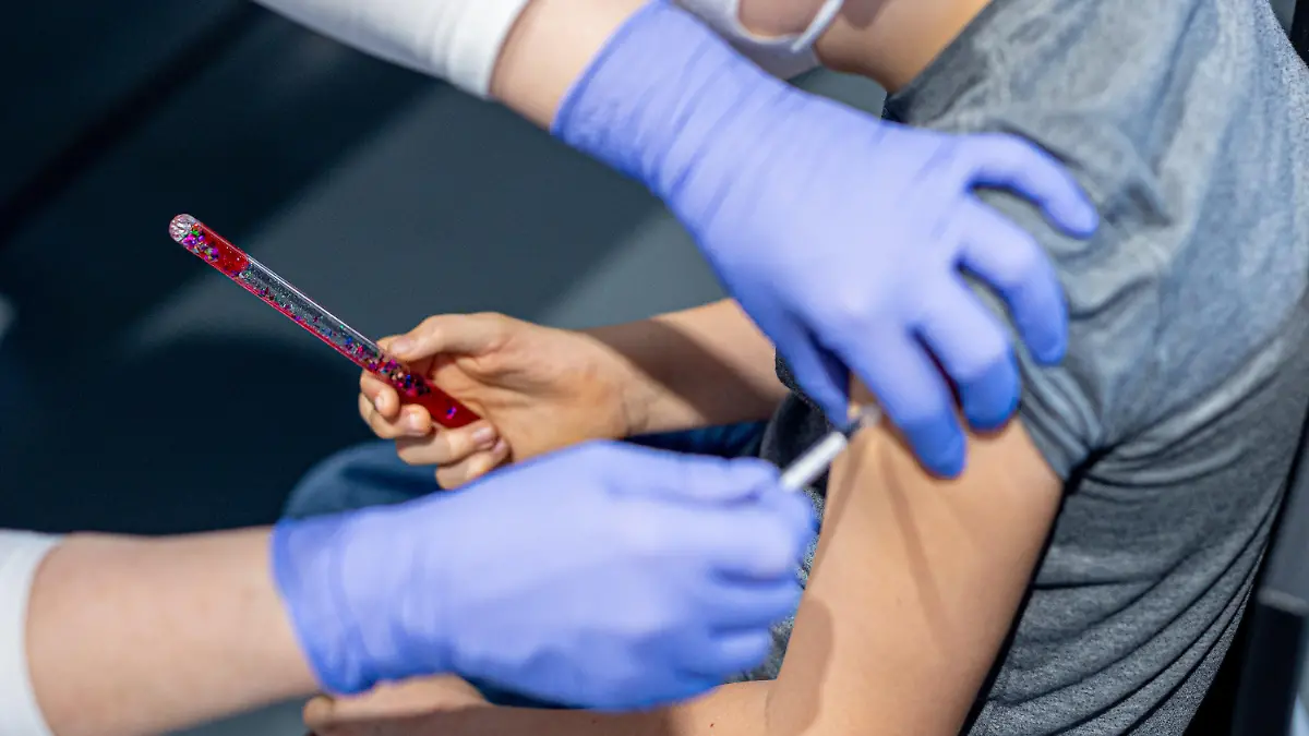 29.01.2022, Niedersachsen, Wolfsburg: Julius lässt sich im phaeno Wolfsburg gegen das Coronavirus impfen und hält dabei zur Ablenkung einen "Zauberstab" in seiner Hand (gestellte Szene). In dem Erlebnismuseum findet eine Kinder-Impfaktion zur Eindämmung des Coronavirus statt. Alle Kinder und Jugendlichen sowie ihre begleitenden Familienmitglieder sollten im Anschluss an die Impfung einen Gratiseintritt ins phaeno erhalten. Foto: Moritz Frankenberg/dpa +++ dpa-Bildfunk +++