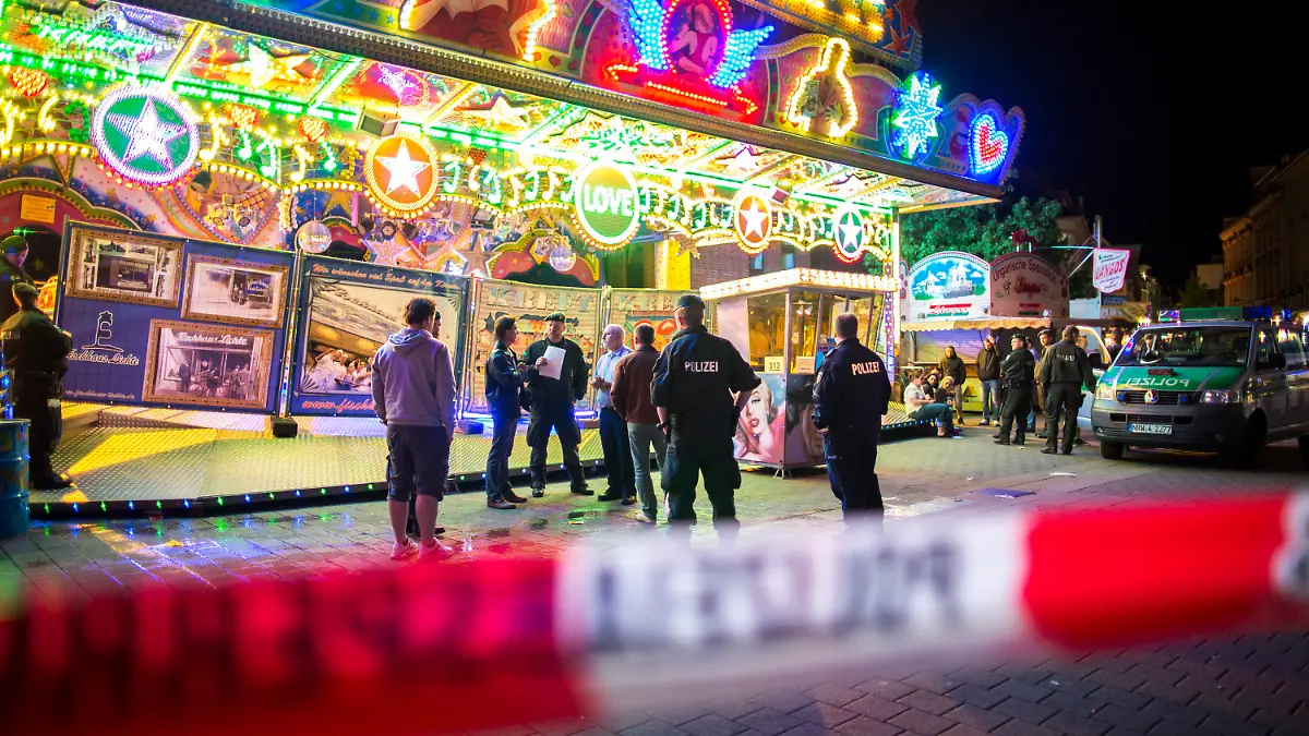 Polizisten stehen am 06.06.2015 in Oberhausen (Nordrhein-Westfalen) auf der Fronleichnamskirmes vor einem Fahrgeschäft. Bei einem Unfall am Samstagabend (06.06.2015) auf einem Kirmes-Fahrgeschäft sind drei Frauen schwer verletzt worden. Foto: Marcel Kusch/dpa (zu dpa «Drei Schwerverletzte bei Kirmes-Unfall in Oberhausen» vom 07.06.2015) +++(c) dpa - Bildfunk+++