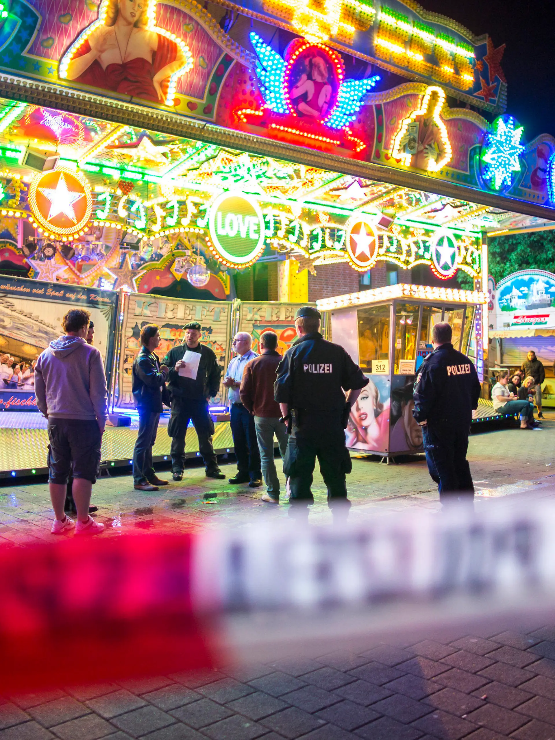 Polizisten stehen am 06.06.2015 in Oberhausen (Nordrhein-Westfalen) auf der Fronleichnamskirmes vor einem Fahrgeschäft. Bei einem Unfall am Samstagabend (06.06.2015) auf einem Kirmes-Fahrgeschäft sind drei Frauen schwer verletzt worden. Foto: Marcel Kusch/dpa (zu dpa «Drei Schwerverletzte bei Kirmes-Unfall in Oberhausen» vom 07.06.2015) +++(c) dpa - Bildfunk+++