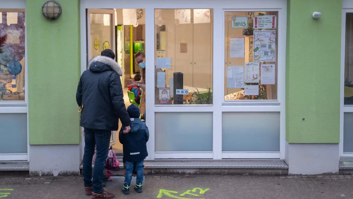 02.02.2022, Hessen, Darmstadt: Ein Vater bringt seine Kinder in eine Kita. Er muss sie vor der Tür abgeben und darf aufgrund der Maßnahmen gegen das Coronavirus nicht in die Räume gehen. Der hessische Elternbund fordert landesweit einheitliche Quarantäne-Regeln in Kitas. Foto: Sebastian Gollnow/dpa +++ dpa-Bildfunk +++