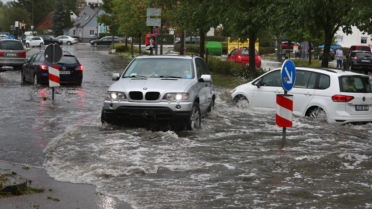 26.08.2023, Bayern, Augsburg: Autos fahren auf einer überfluteten Straße. Gewitter mit starkem Wind und Hagel haben am Samstagnachmittag für zahlreiche Einsätze in Schwaben gesorgt. Foto: Karl-Josef Hildenbrand/dpa +++ dpa-Bildfunk +++