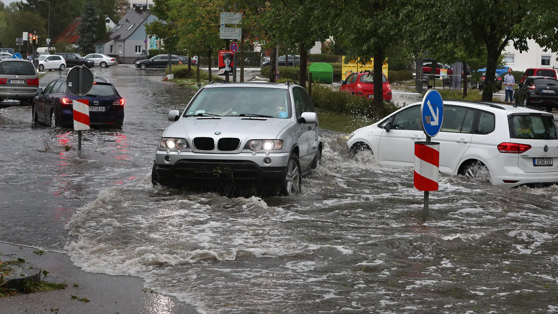 26.08.2023, Bayern, Augsburg: Autos fahren auf einer überfluteten Straße. Gewitter mit starkem Wind und Hagel haben am Samstagnachmittag für zahlreiche Einsätze in Schwaben gesorgt. Foto: Karl-Josef Hildenbrand/dpa +++ dpa-Bildfunk +++