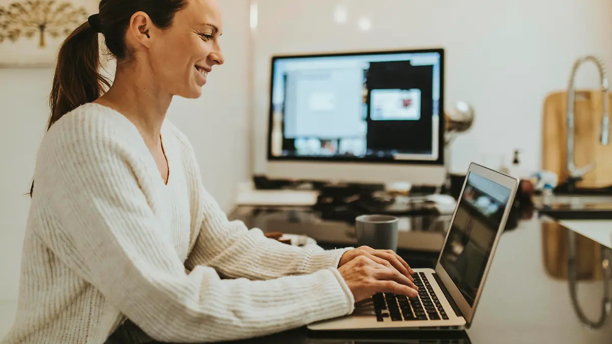  Woman on video call with friend through laptop at kitchen island model released Symbolfoto property released DMGF00347