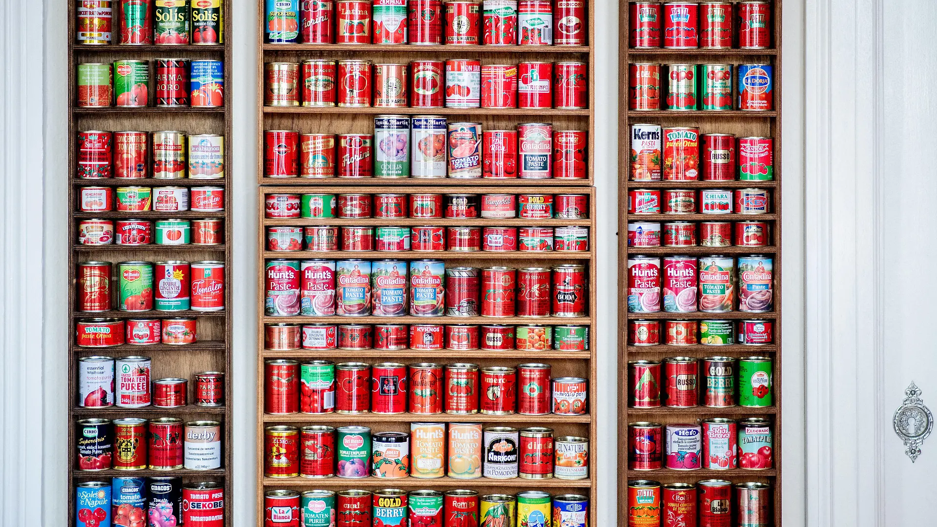 01.02.2022, Niedersachsen, Oldenburg: Zahlreiche Tomatenmarkdosen aus verschiedenen Ländern stehen in einem Regal im Esszimmer von Sammlerin Tuchenhagen. Die Oldenburgerin hat seit 1983 rund 490 verschiedene Tomatenmarkdosen aus aller Wellt gesammelt. Foto: Hauke-Christian Dittrich/dpa +++ dpa-Bildfunk +++