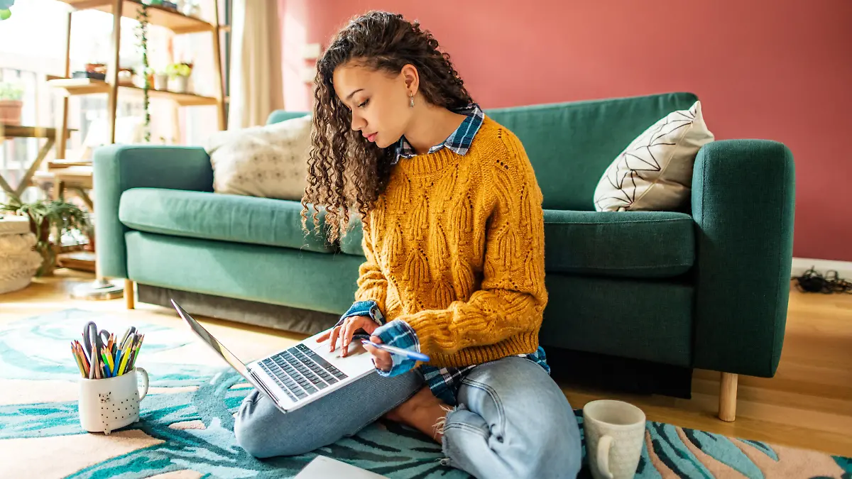 Attractive young woman sitting on the floor of her living room and use laptop