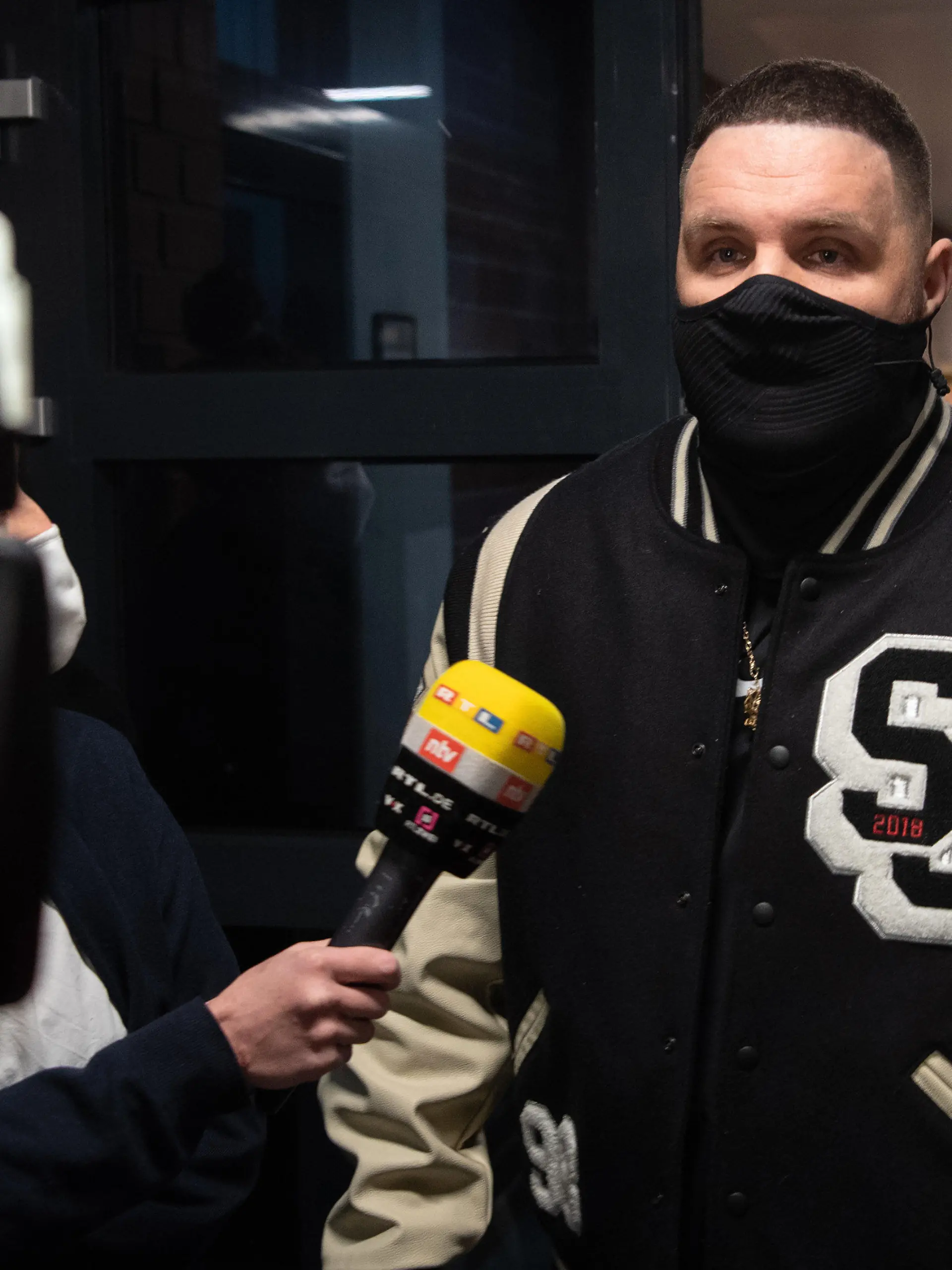 15.01.2021, Berlin: Rapper Fler, bürgerlich Patrick Losensky, gibt auf dem Weg zum Gerichtssaal einem Fernsehsender ein Interview. Dem 38-Jährigen werden Beleidigung, Sachbeschädigung, versuchte Nötigung und Fahren ohne Fahrerlaubnis vorgeworfen. Immer wieder soll der Musiker verschiedene Menschen wüst verunglimpft und beleidigt haben. Das Verfahren hatte bereits im November 2020 begonnen, musste dann aber wegen Erkrankung des Angeklagten ausgesetzt werden. Foto: Paul Zinken/dpa-Zentralbild/dpa +++ dpa-Bildfunk +++