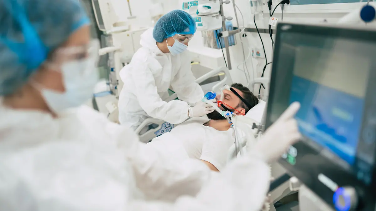Coronavirus covid-19 infected patient in a quarantine ward at the hospital with doctors in protective suits while they making disease treatment of him