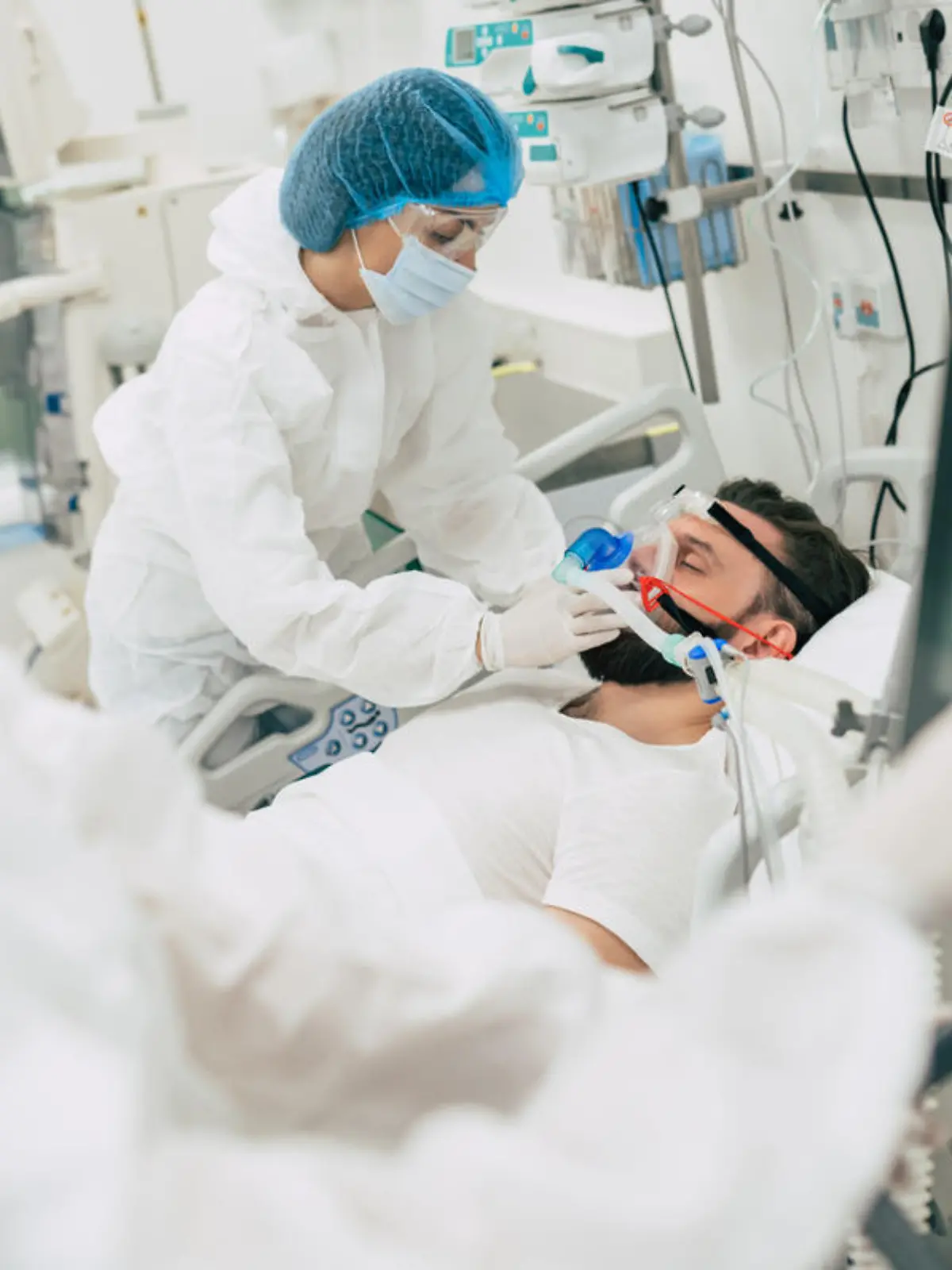 Coronavirus covid-19 infected patient in a quarantine ward at the hospital with doctors in protective suits while they making disease treatment of him