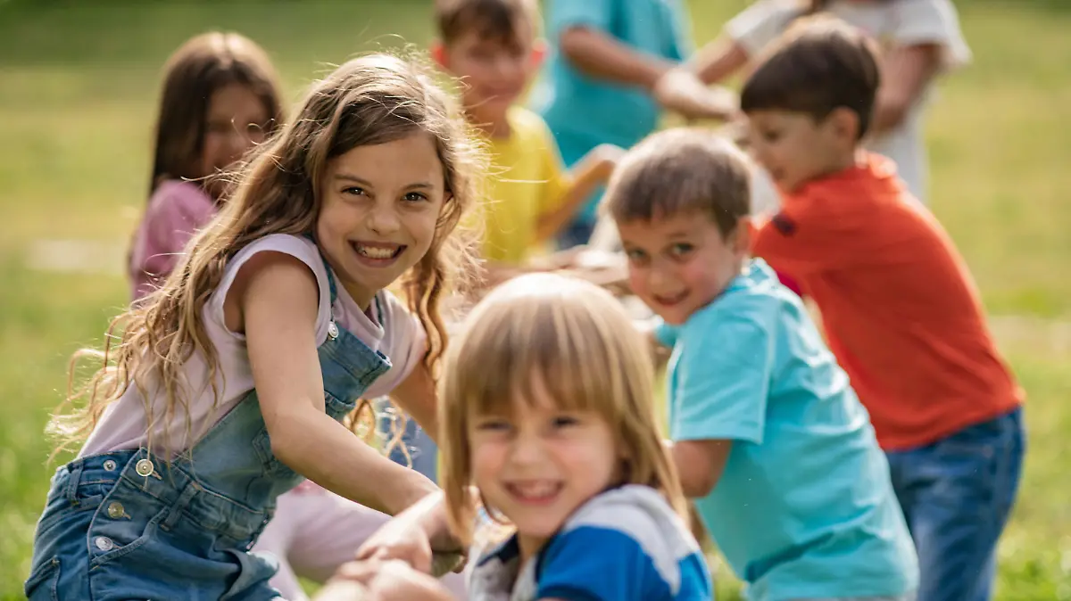 Smiling kids pulling a rope in park