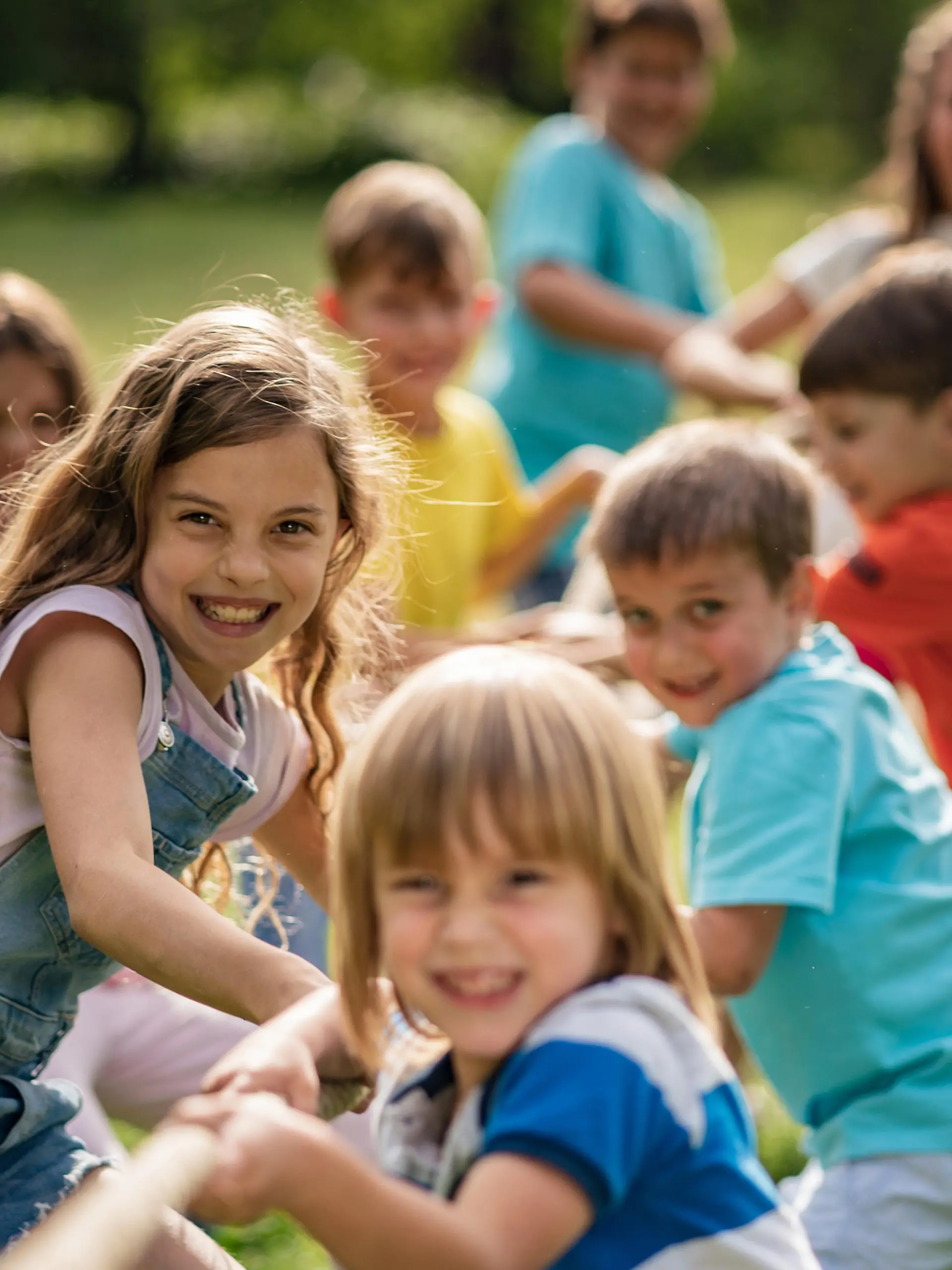 Smiling kids pulling a rope in park