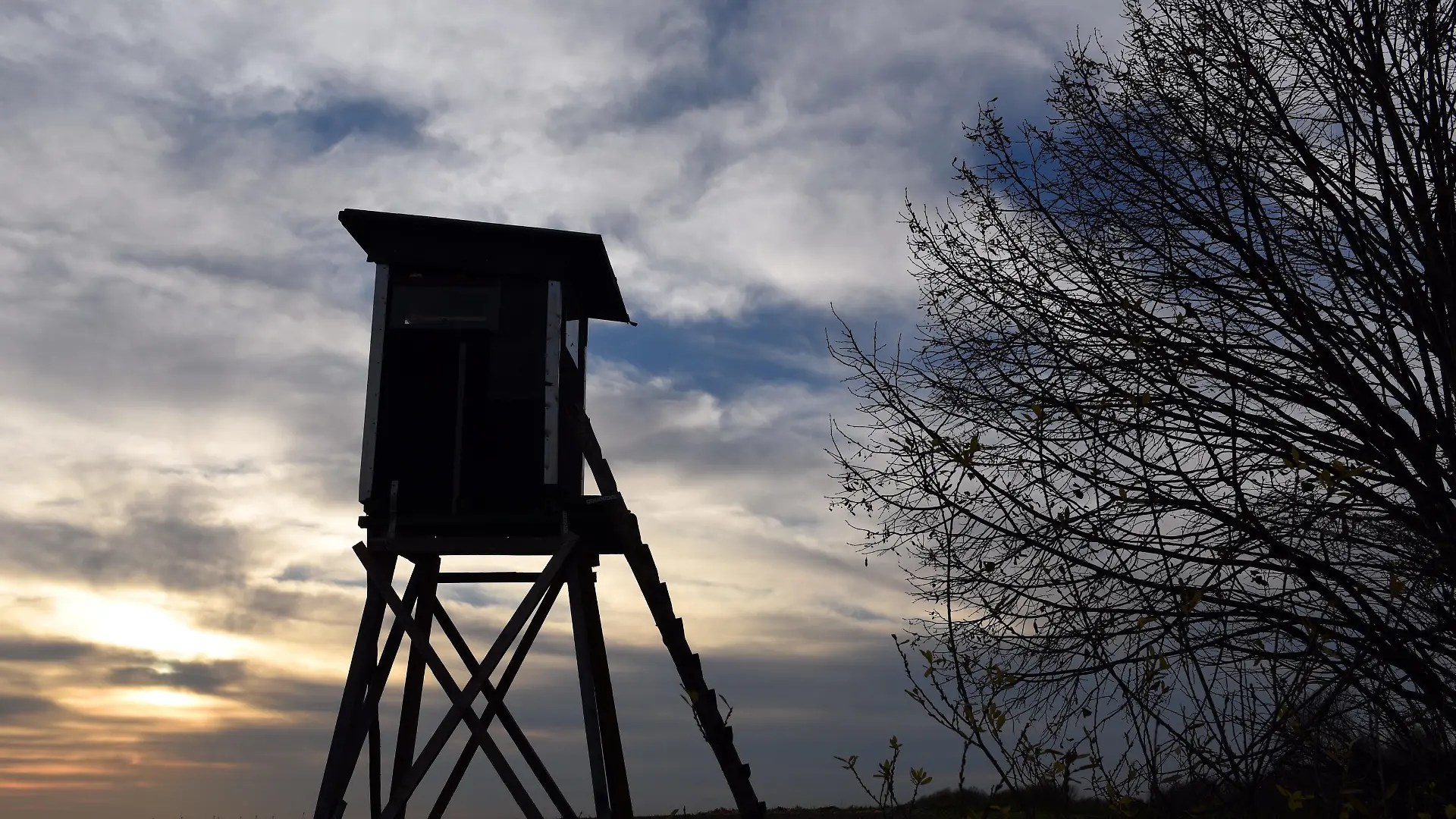 Ein Jagdhochsitz steht im Gegenlicht der untergehenden Sonn im Braunkohle-Tagebau Garzweiler bei Grevenbroich (Nordrhein-Westfalen) (Foto vom 03.12.2015). Foto: Horst Ossinger/dpa | Verwendung weltweit