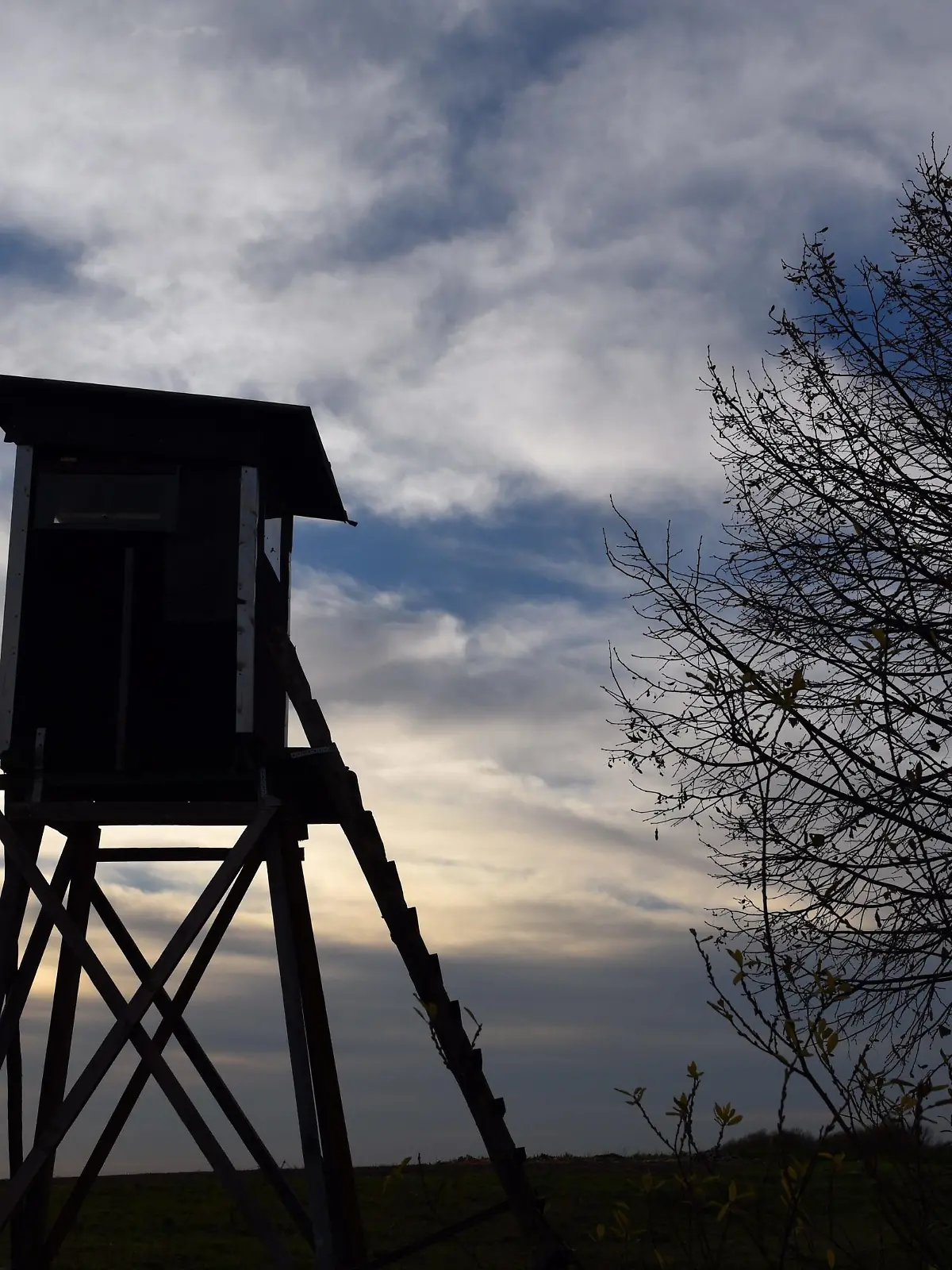 Ein Jagdhochsitz steht im Gegenlicht der untergehenden Sonn im Braunkohle-Tagebau Garzweiler bei Grevenbroich (Nordrhein-Westfalen) (Foto vom 03.12.2015). Foto: Horst Ossinger/dpa | Verwendung weltweit