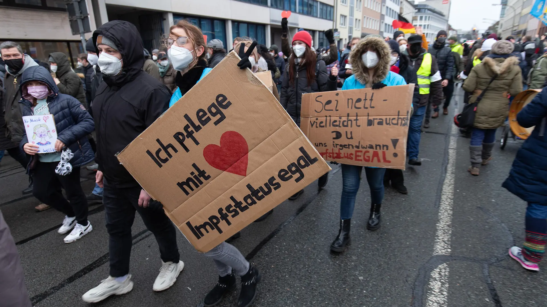 Ein Banner „Ich pflege mit Herz - Impfstatus egal“ wird vom Demonstrant einer Versammlung gehalten. Die Teilnehmer demonstrieren gegen die Corona-Politik.