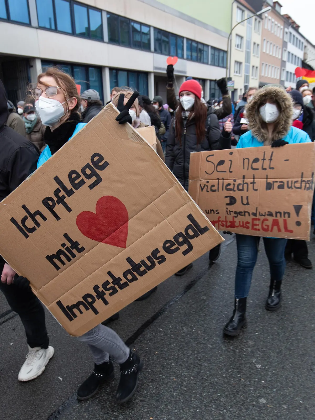 Ein Banner „Ich pflege mit Herz - Impfstatus egal“ wird vom Demonstrant einer Versammlung gehalten. Die Teilnehmer demonstrieren gegen die Corona-Politik.