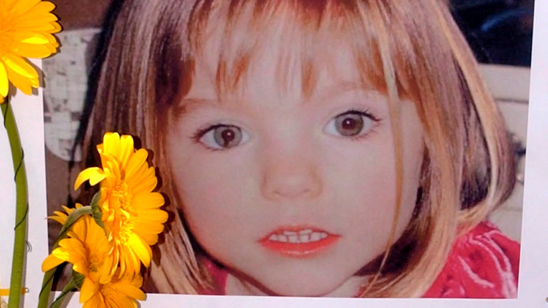 ARCHIV - 12.05.2007, Portugal, Lagos: Blumen stehen vor einem Bild, das die verschwundenen Madeleine McCann (Maddie) auf einem Foto zeigt, das ihre Eltern im Zusammenhang mit dem Verschwinden des Kindes veröffentlich haben. (zu dpa: "Fall Maddie: Ermittler halten 44-Jährigen weiter für tatverdächtig") Foto: Luis Forra/LUSA FILE/dpa +++ dpa-Bildfunk +++