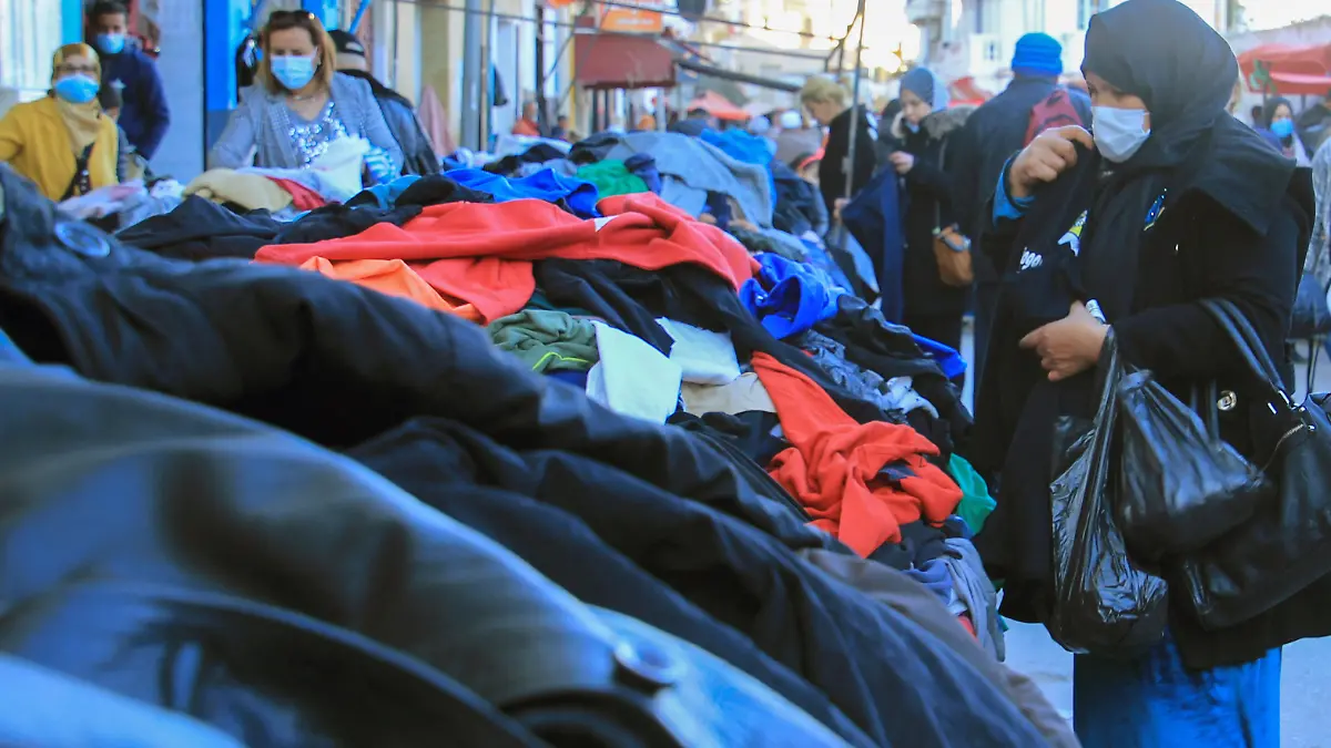 Kunden schauen sich gebrauchte Kleidungsstücke auf einem zentralen Markt in Tunesiens Hauptstadt an. (zu dpa: «Minderwertige Altkleider: Afrika wird zur «Müllkippe des Westens»»)