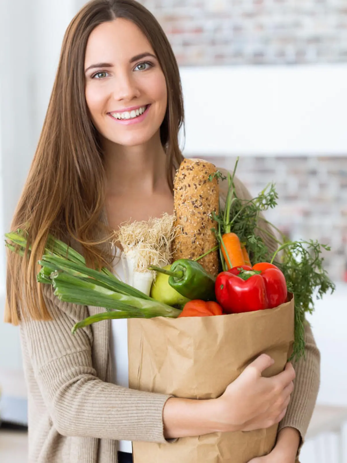 Portrait of beautiful young woman with vegetables in grocery bag at home.