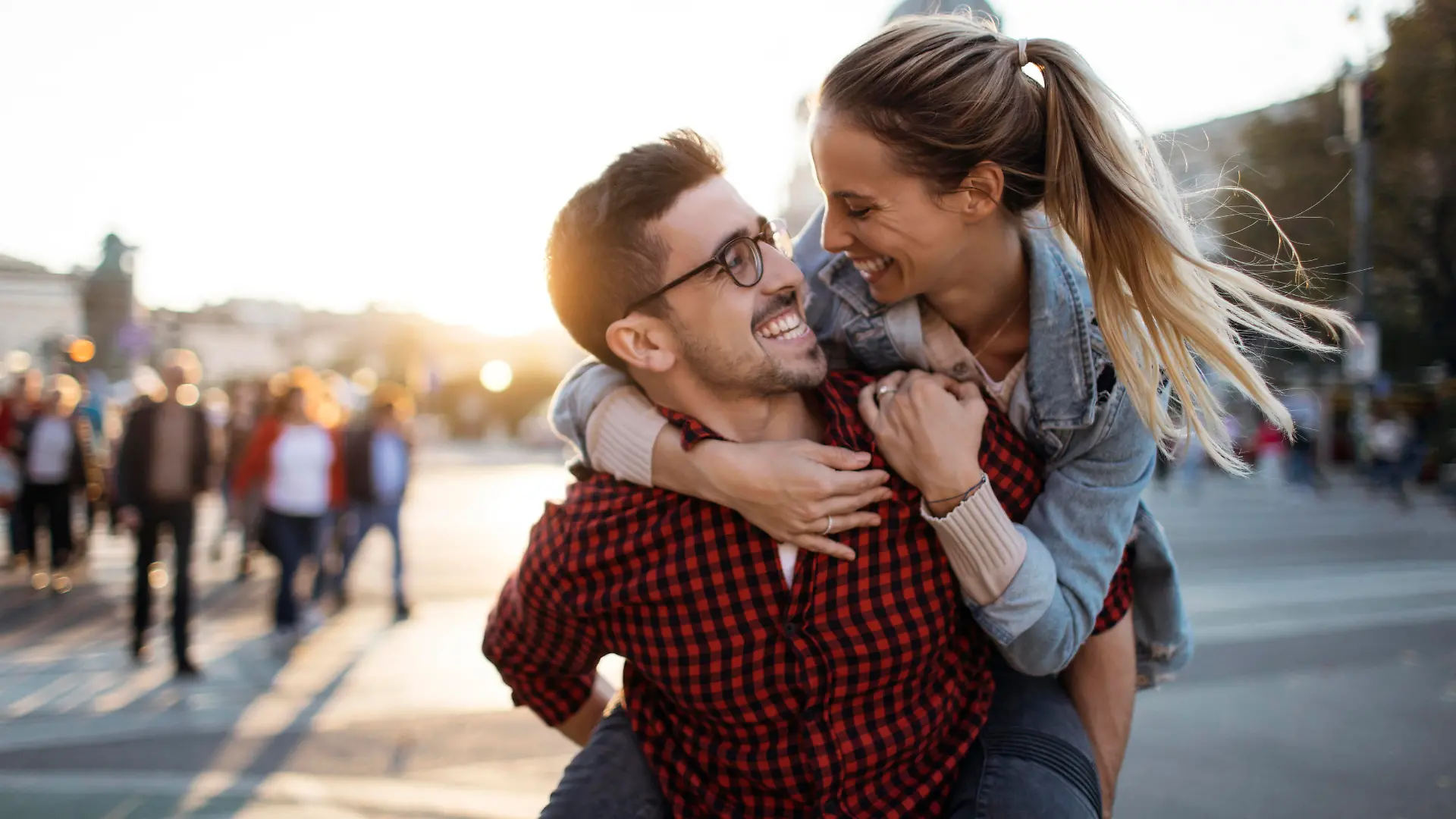 Happy boyfriend smiling and carrying girlfriend on his back outdoors