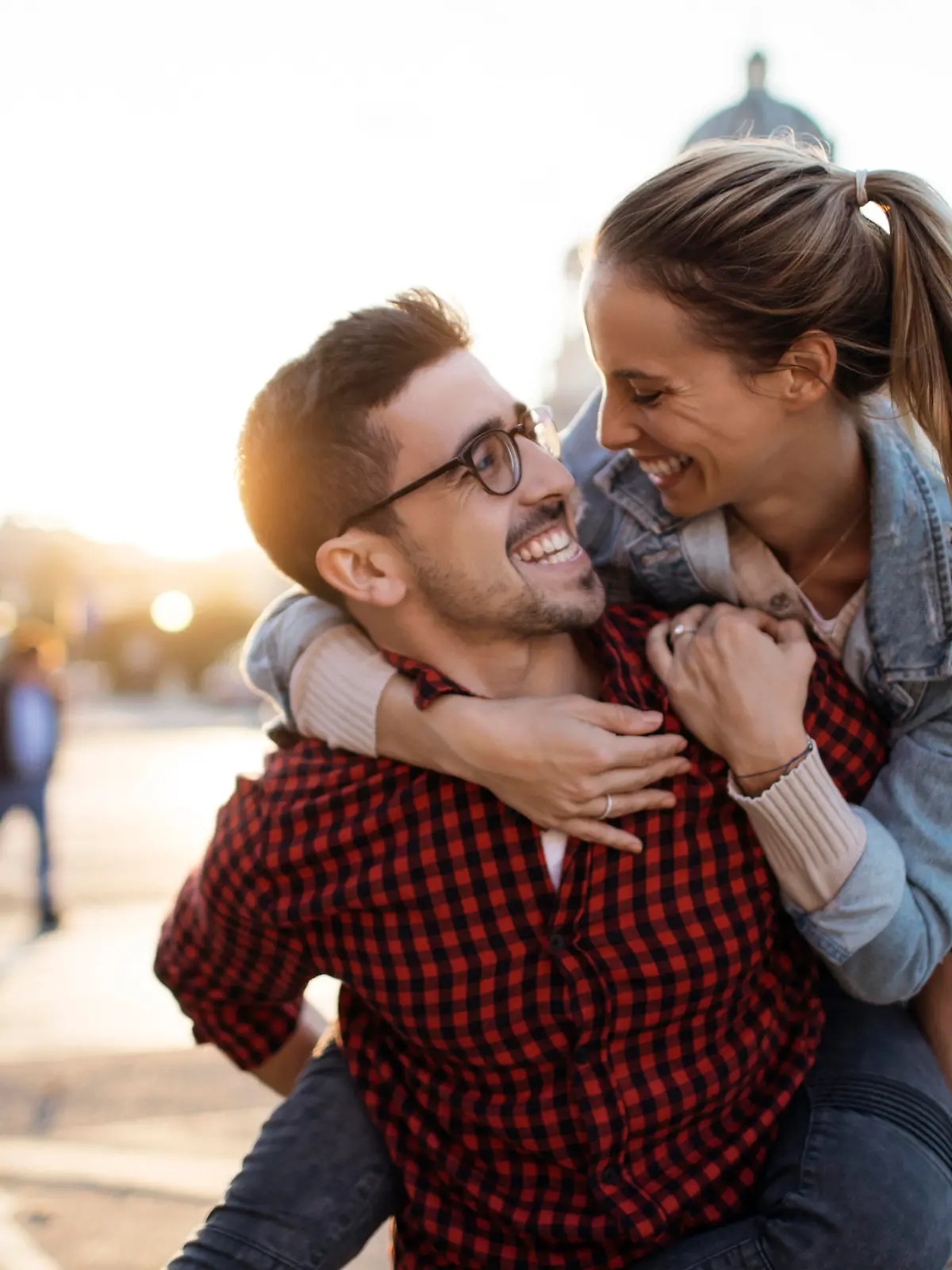 Happy boyfriend smiling and carrying girlfriend on his back outdoors
