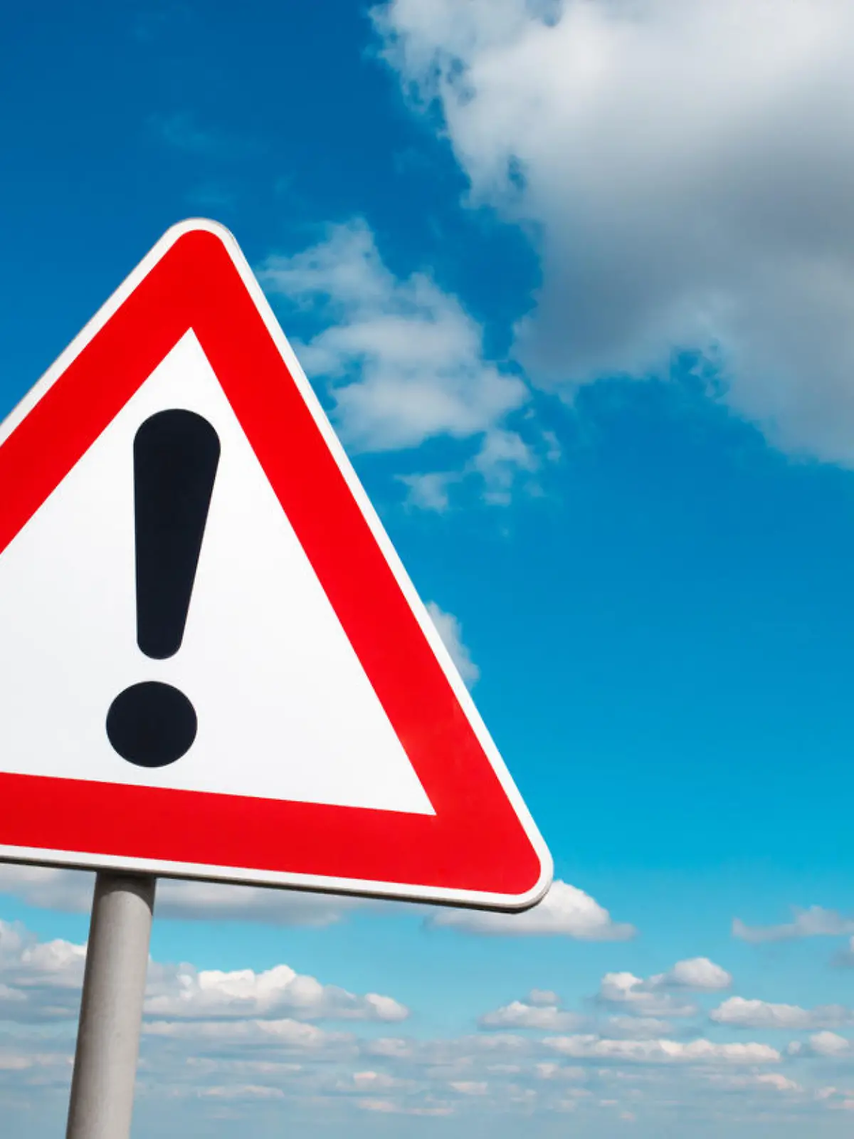Warning road sign against a cloudy sky.