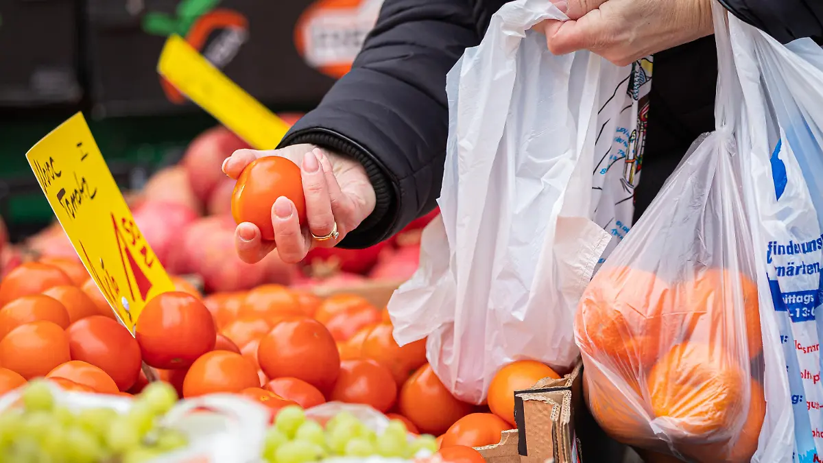 PRODUKTION - 29.01.2022, Niedersachsen, Hannover: Eine Kundin begutachtet eine Tomate an einem Stand auf einem Wochenmarkt. Nach dem Preisschub im Jahr 2021 hoffen Verbraucher in Deutschland auf Entspannung bei der Teuerung. Wie sich die Inflation im Januar 2022 entwickelt hat, gibt das Statistische Bundesamt am Nachmittag (31.01.2022) in einer ersten Schätzung bekannt. Im Dezember 2021 waren die Verbraucherpreise gegenüber dem Vorjahresmonat um 5,3 Prozent gestiegen. Foto: Moritz Frankenberg/dpa +++ dpa-Bildfunk +++