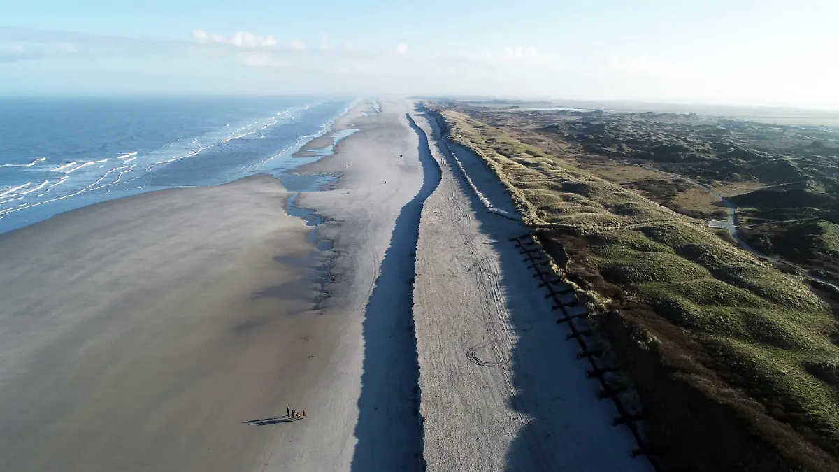 HANDOUT - 10.01.2022, Niedersachsen, Langeoog: Eine deutliche, etwa 500 Meter lange Abbruchkante hat sich nach den vergangenen Sturmfluten am Strand von Langeoog vor den Dünen des sogenannten Pirolatals gebildet (Luftaufnahme mit einer Drohne). Die Kante sei nach den Strandaufspülungen 2020 zu erwarten gewesen, teilte der für Küstenschutz zuständige Landesbetrieb mit. Das Sanddepot wird nach jeder Sturmflut schmaler und sichert so die Schutzdünen der Insel gegen Wellen und Sandabbrüche. (zu dpa: "Abbruchkante am Strand von Langeoog - keine Gefahr für Küstenschutz") Foto: -/NLWKN/dpa - ACHTUNG: Nur zur redaktionellen Verwendung im Zusammenhang mit der aktuellen Berichterstattung und nur mit vollständiger Nennung des vorstehenden Credits +++ dpa-Bildfunk +++