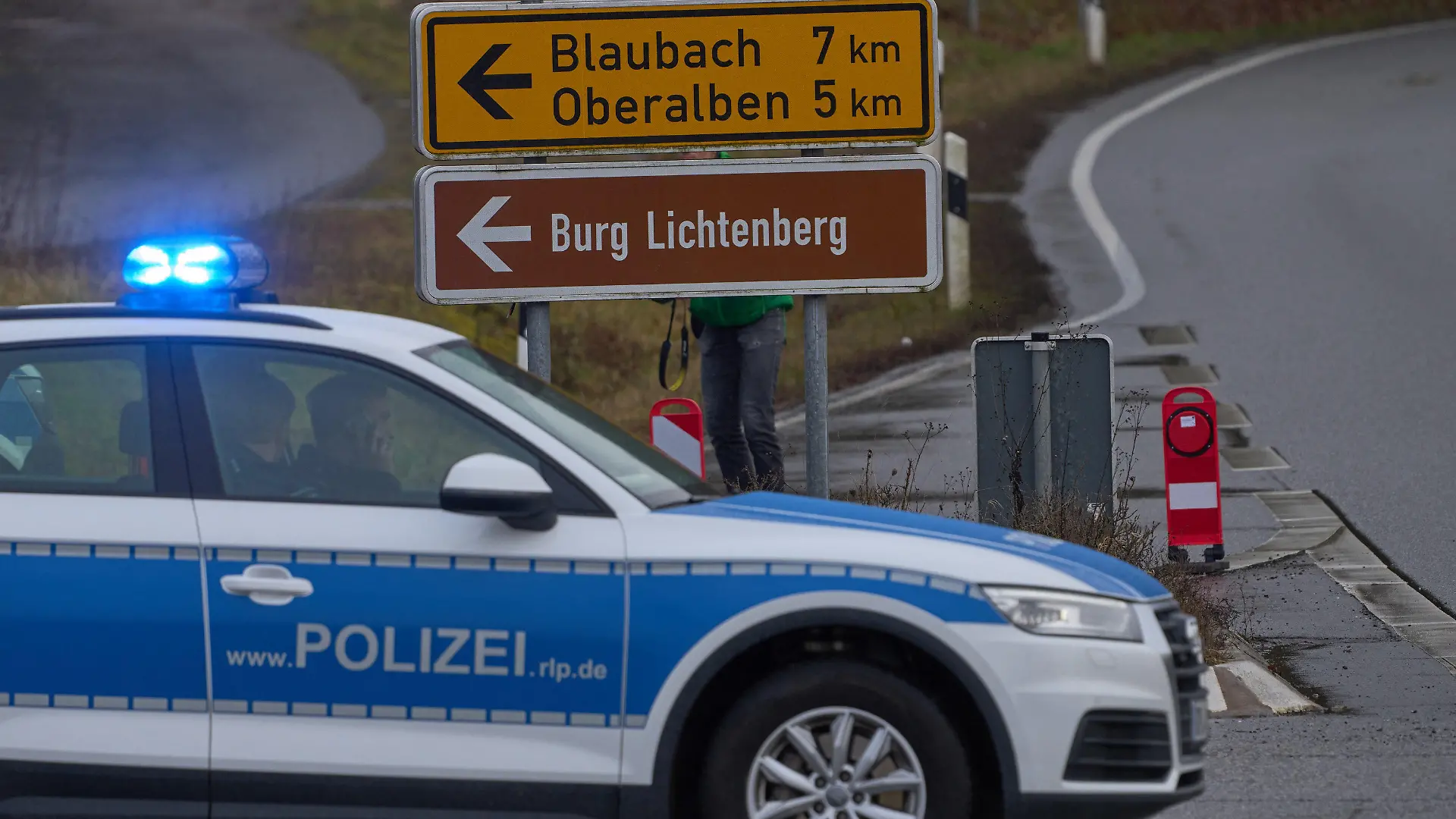 31.01.2022, Rheinland-Pfalz, Kusel: Polizeibeamte sperren die Zufahrt zum Tatort, wo zwei Polizeibeamte bei einer Verkehrskontrolle durch Schüsse tödlich verletzt wurden. Die tödlichen Schüsse fielen nach Polizei-Angaben bei einer routinemäßigen Verkehrskontrolle. Foto: Thomas Frey/dpa +++ dpa-Bildfunk +++