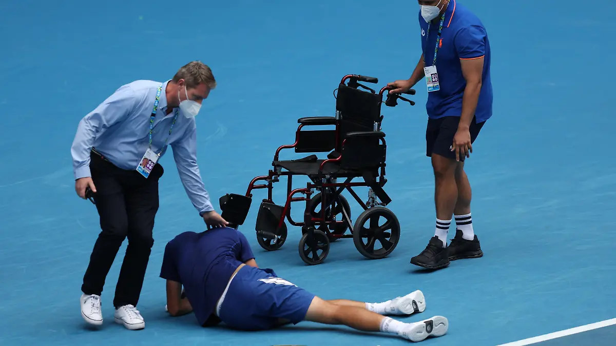 MELBOURNE, AUSTRALIA - JANUARY 29: Jakub Mensik of Czech Republic is assisted from the court after playing his Junior Boy's Singles Final match against Bruno Kuzuhara of United States during day 13 of the 2022 Australian Open at Melbourne Park on January 29, 2022 in Melbourne, Australia. (Photo by Graham Denholm/Getty Images)