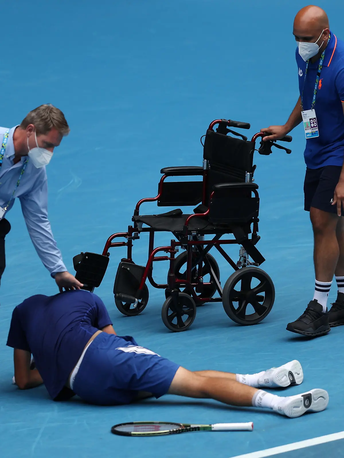 MELBOURNE, AUSTRALIA - JANUARY 29: Jakub Mensik of Czech Republic is assisted from the court after playing his Junior Boy's Singles Final match against Bruno Kuzuhara of United States during day 13 of the 2022 Australian Open at Melbourne Park on January 29, 2022 in Melbourne, Australia. (Photo by Graham Denholm/Getty Images)