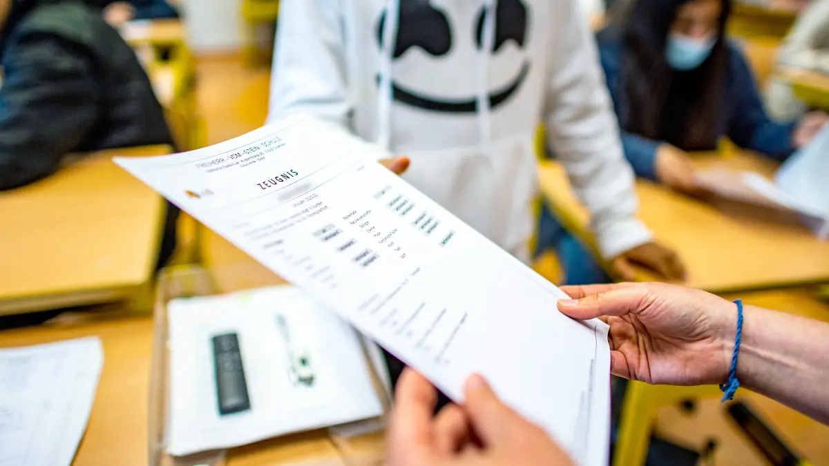 02.07.2021, Nordrhein-Westfalen, Gütersloh: Die Klassenlehrerin übergibt das Zeugnis eines Schülers der Klasse 9b der Freiherr-vom-Stein-Schule in Gütersloh. An den 5400 Schulen in Nordrhein-Westfalen ist am heutigen Freitag der letzte Schultag vor den Sommerferien. 2,5 Millionen Jungen und Mädchen bekommen ihre Zeugnisse. Foto: David Inderlied/dpa +++ dpa-Bildfunk +++